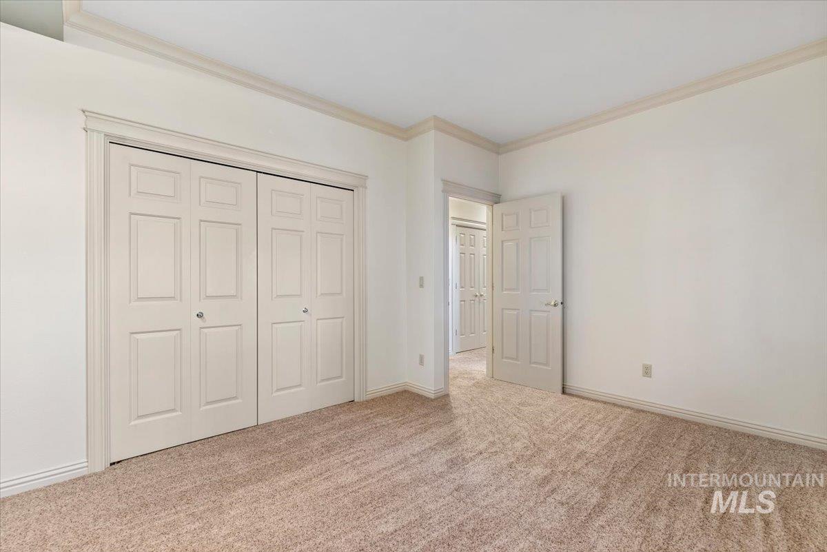 Unfurnished bedroom with ornamental molding, a closet, and light colored carpet