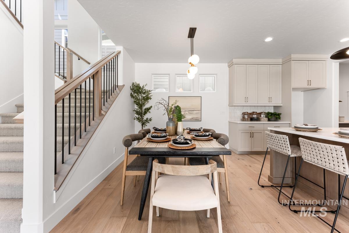 Open concept living space featuring wood-finish flooring, a contemporary staircase with wood handrails and black balusters, and a dining area with a modern chandelier