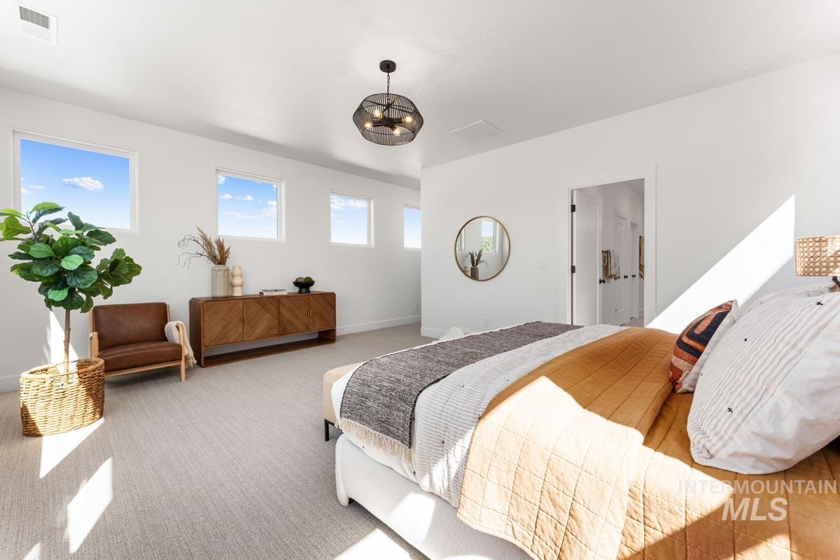 Spacious room featuring multiple rectangular windows, light-toned carpeting, a modern black chandelier, and a wood-finish credenza