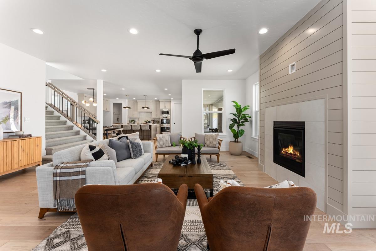 Spacious living area featuring a fireplace with shiplap surround, wood-finish flooring, recessed lighting, and an open concept layout