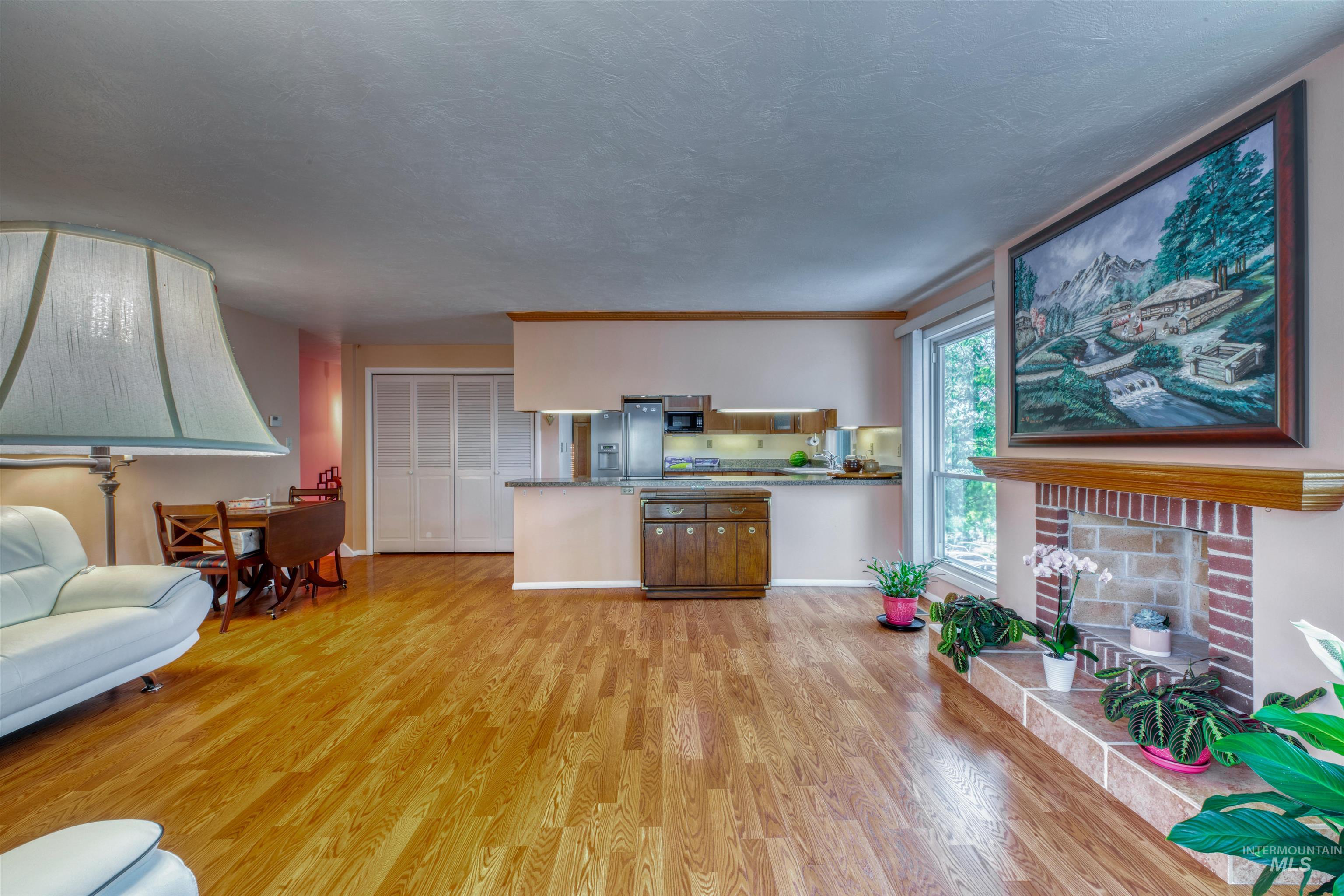 Living room with light wood-type flooring, a fireplace, and a textured ceiling
