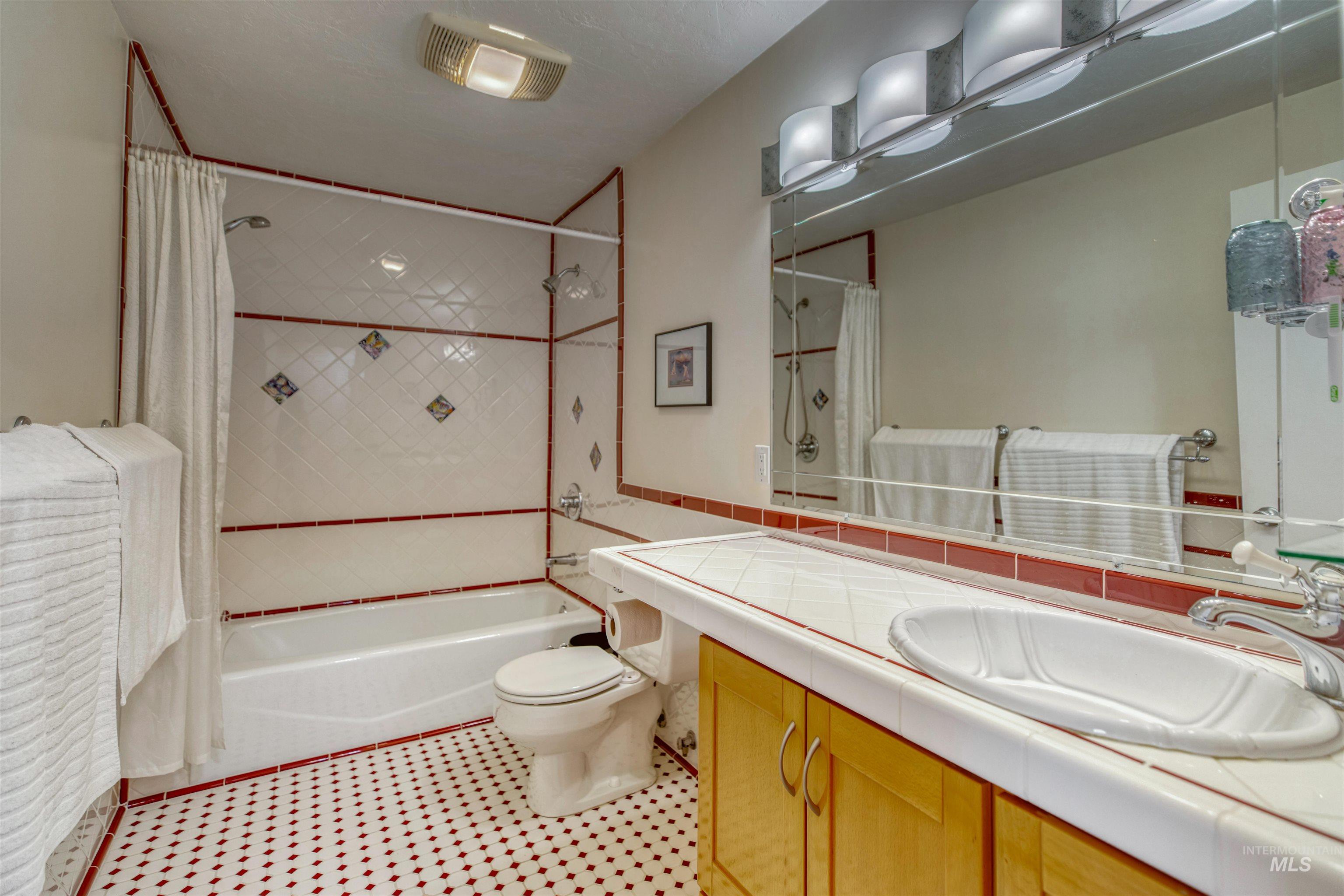Full bath with vanity, shower / tub combo, tile walls, and light tile patterned floors
