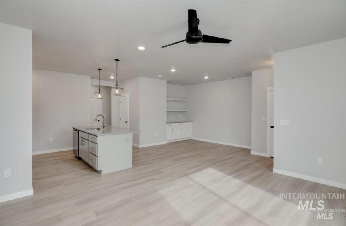 Kitchen with a center island with sink, light wood-type flooring, ceiling fan, and open floor plan