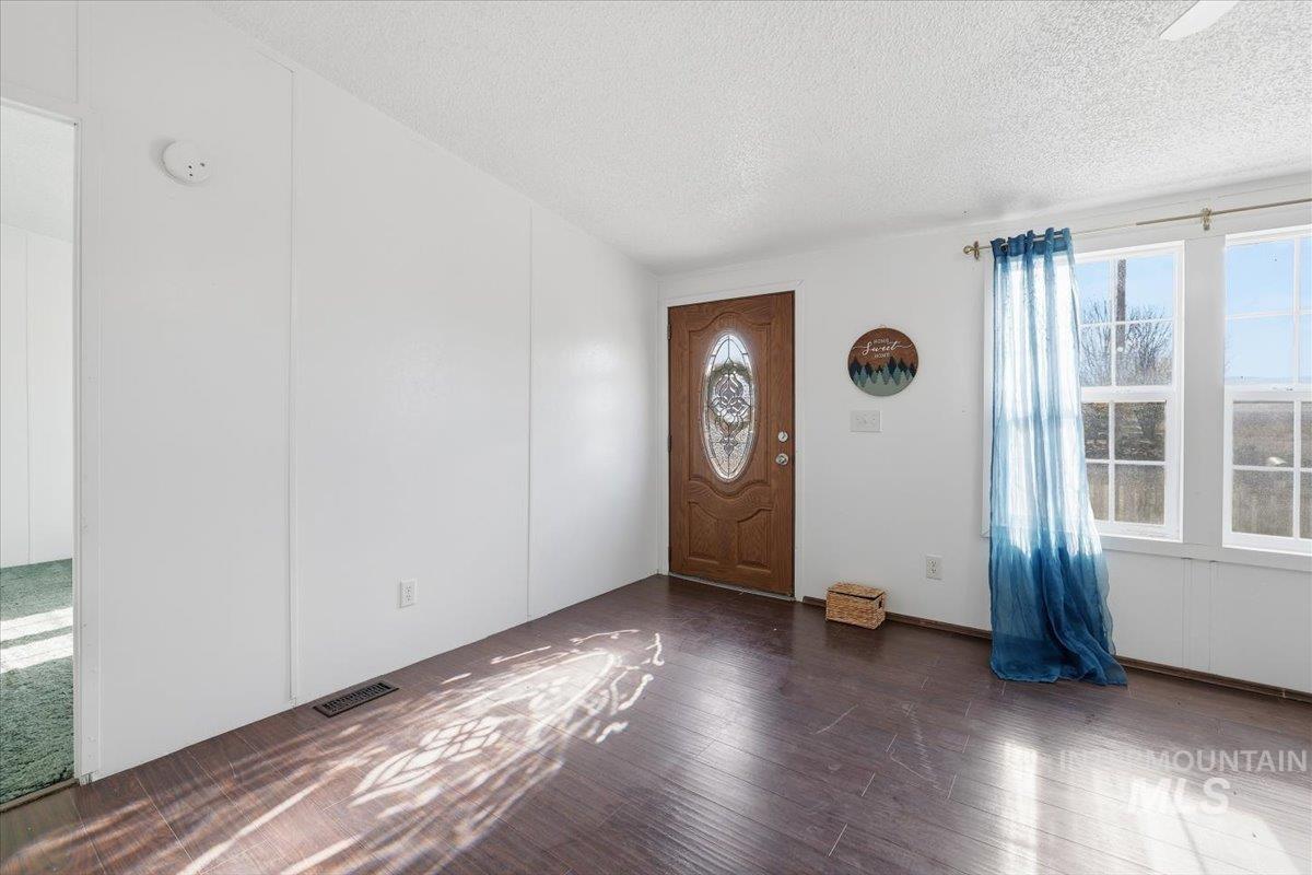 Entrance foyer featuring a textured ceiling and dark wood finished floors