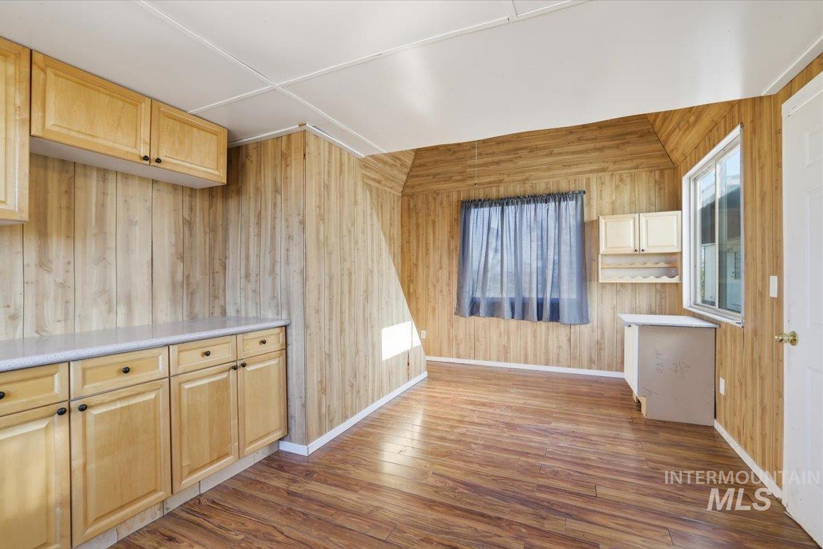 Unfurnished dining area featuring wooden walls and hardwood / wood-style flooring