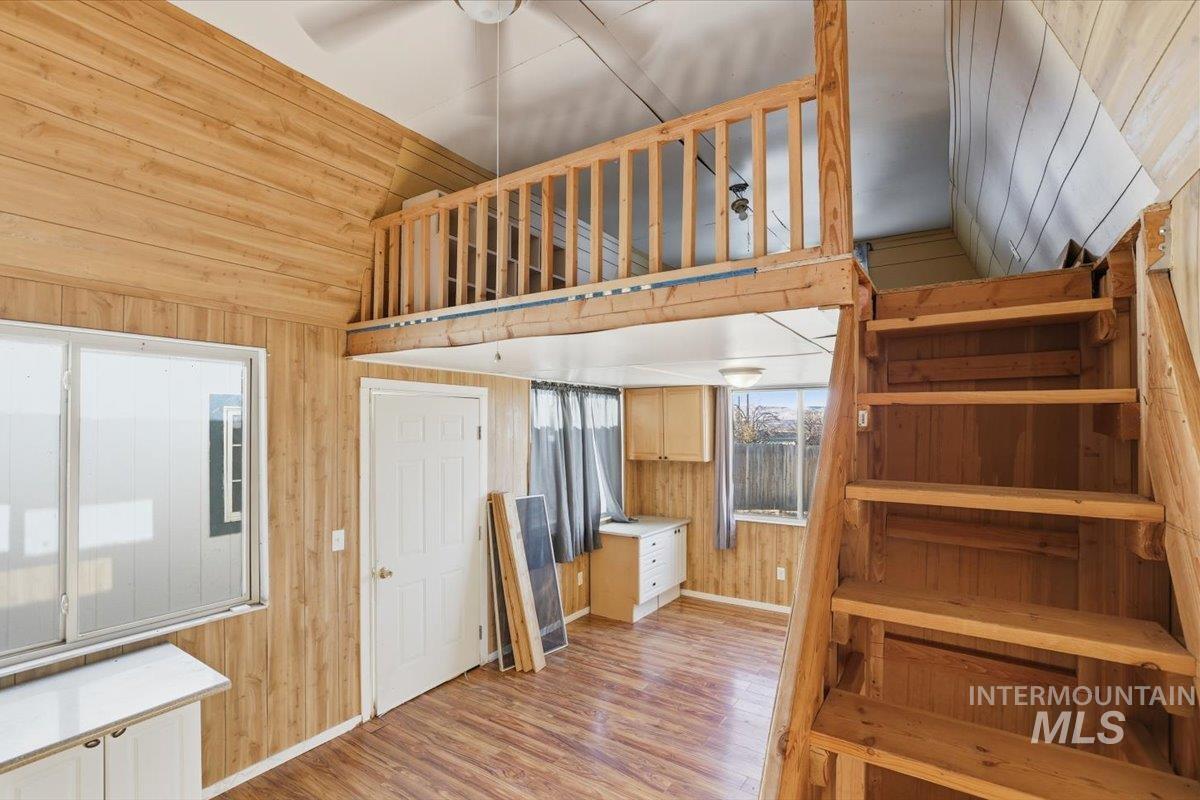 Kitchen featuring wood walls, light wood-style flooring, lofted ceiling, a ceiling fan, and wood ceiling