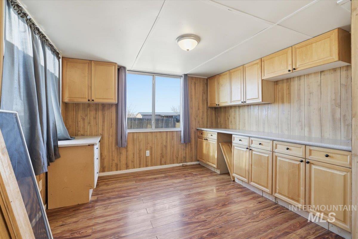 Kitchen featuring wood walls, light wood-type flooring, light countertops, light brown cabinetry, and built in desk