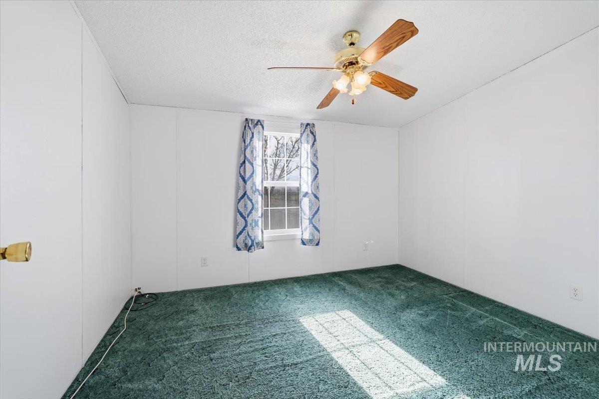 Empty room with carpet, a textured ceiling, and ceiling fan