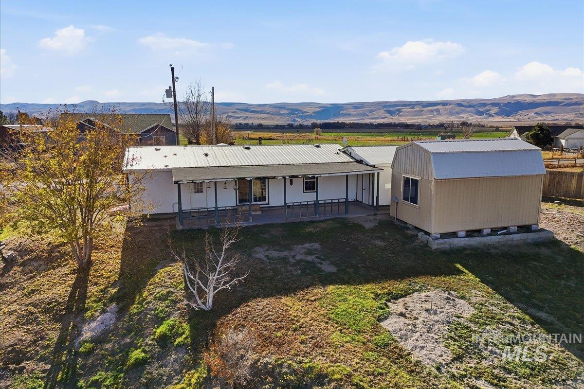 Back of house with a mountain view, a lawn, and a metal roof