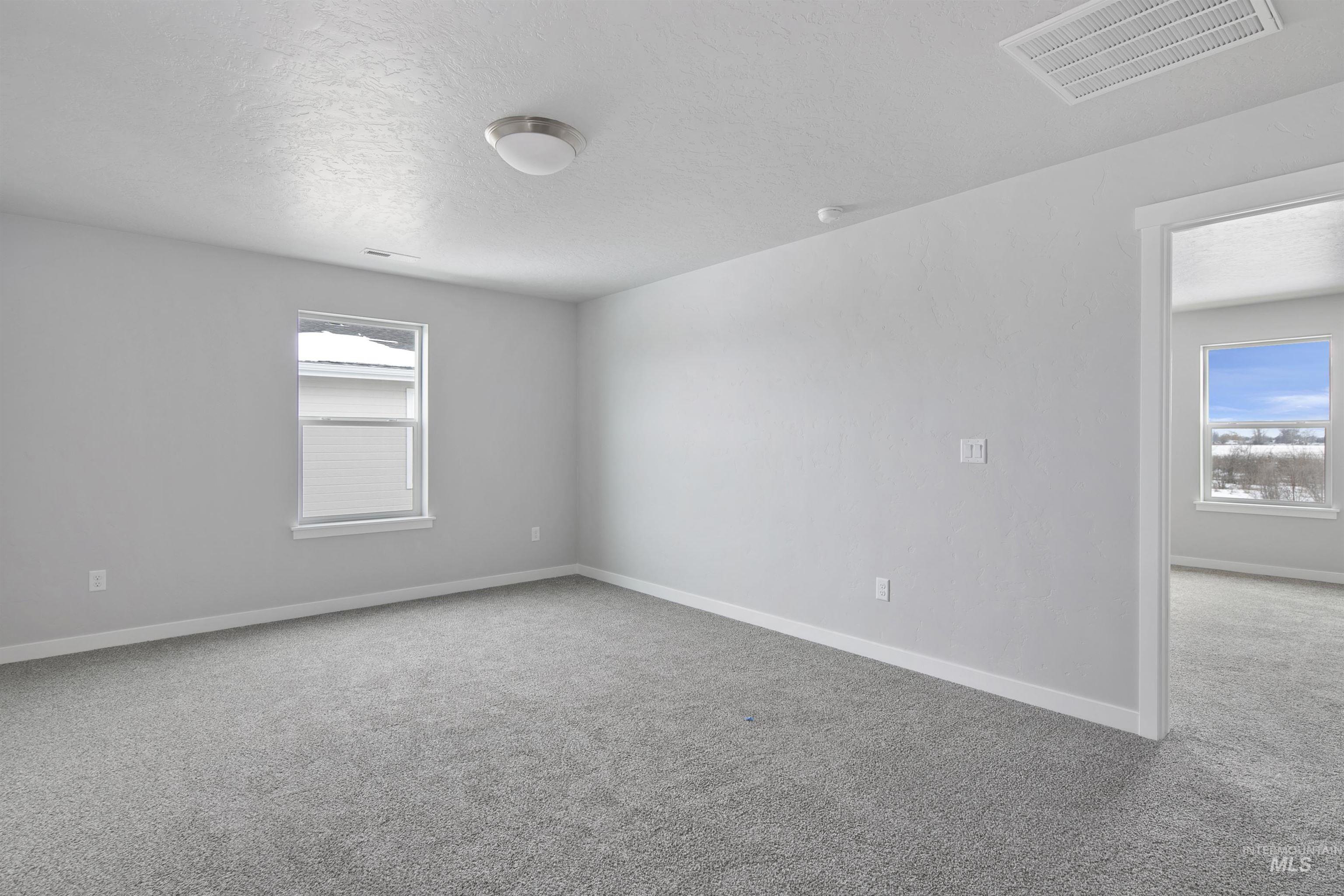 Empty room with light colored carpet and a textured ceiling