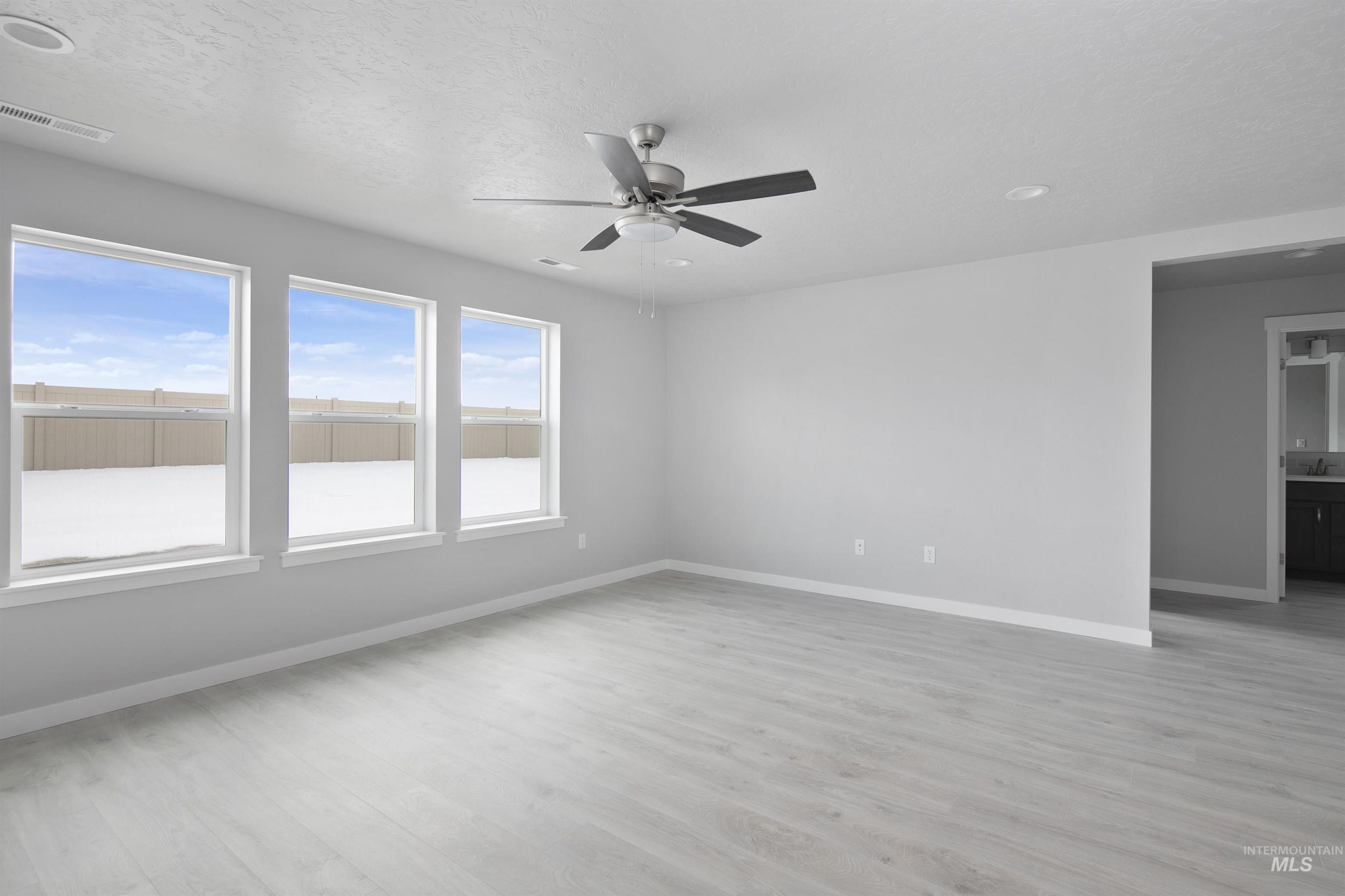 Unfurnished room with light wood-style flooring, a textured ceiling, and a ceiling fan