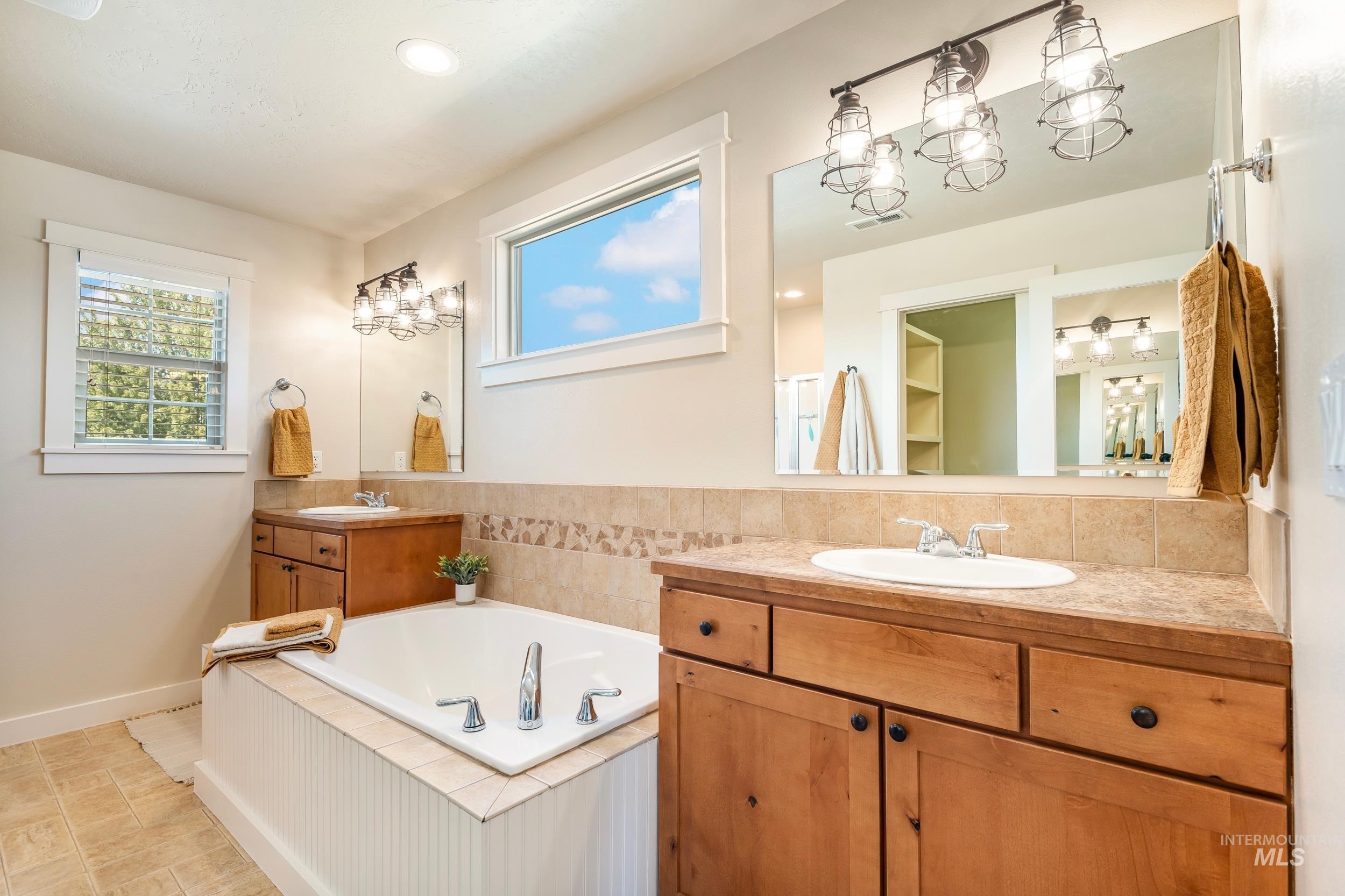 Bathroom featuring two vanities, a bath, and recessed lighting