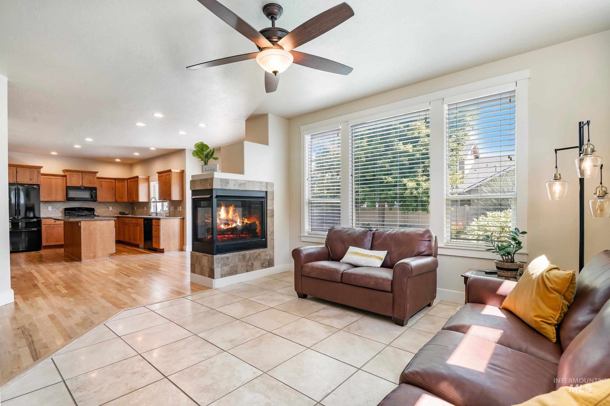 Living room featuring light tile patterned flooring, a tile fireplace, a ceiling fan, and recessed lighting