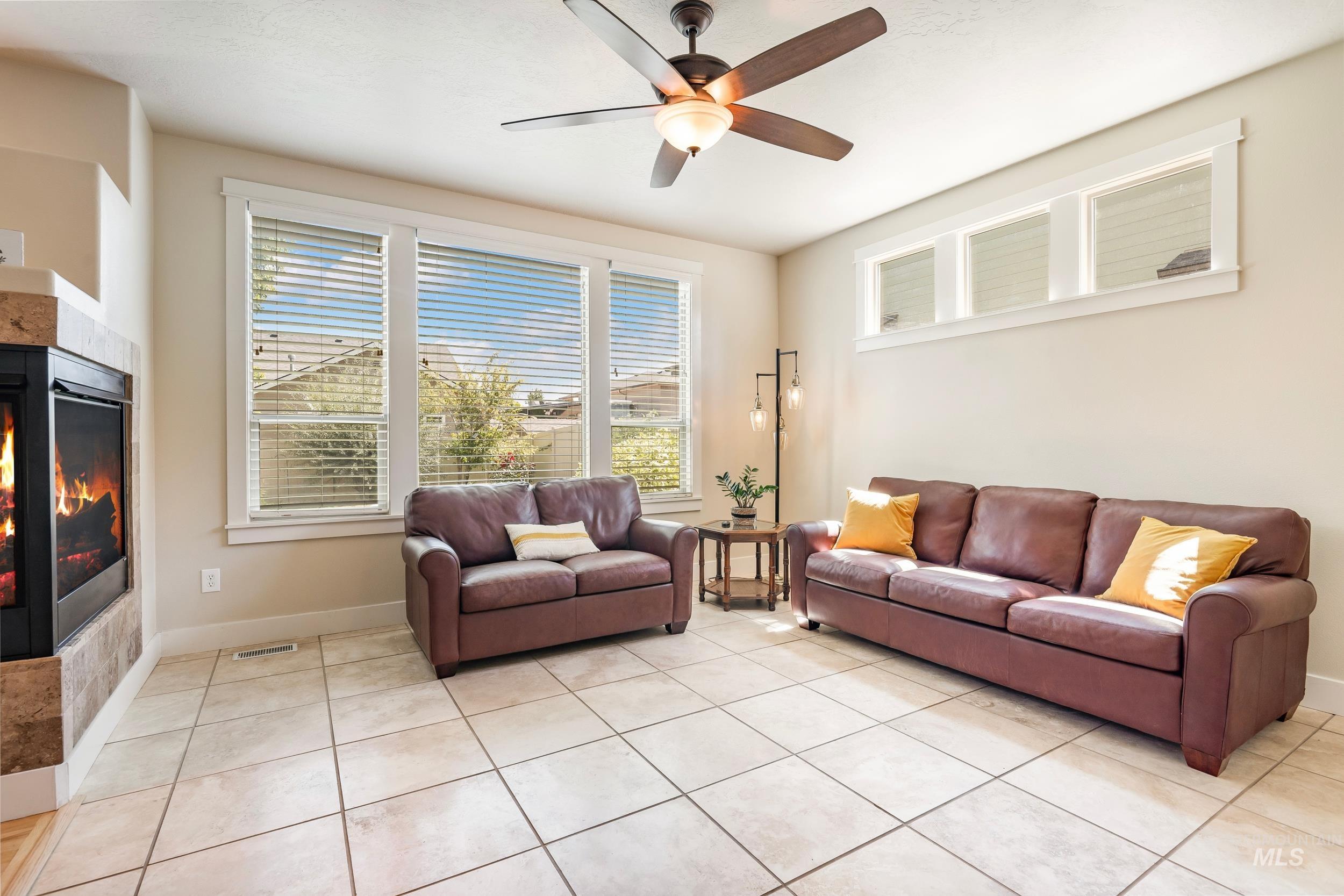 Living area featuring light tile patterned flooring, plenty of natural light, and a fireplace