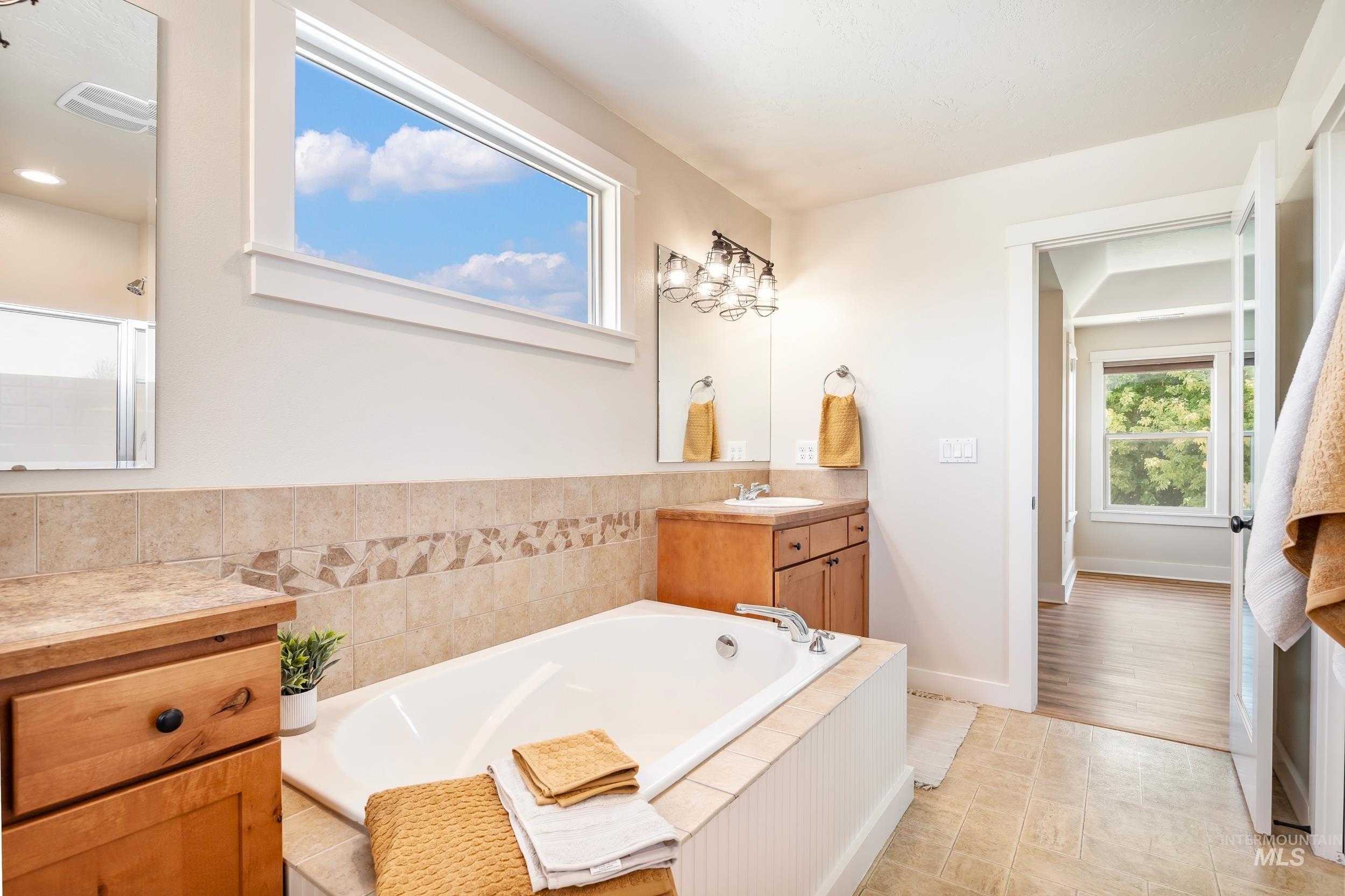 Full bathroom featuring vanity, a bath, a shower with shower door, and light tile patterned floors