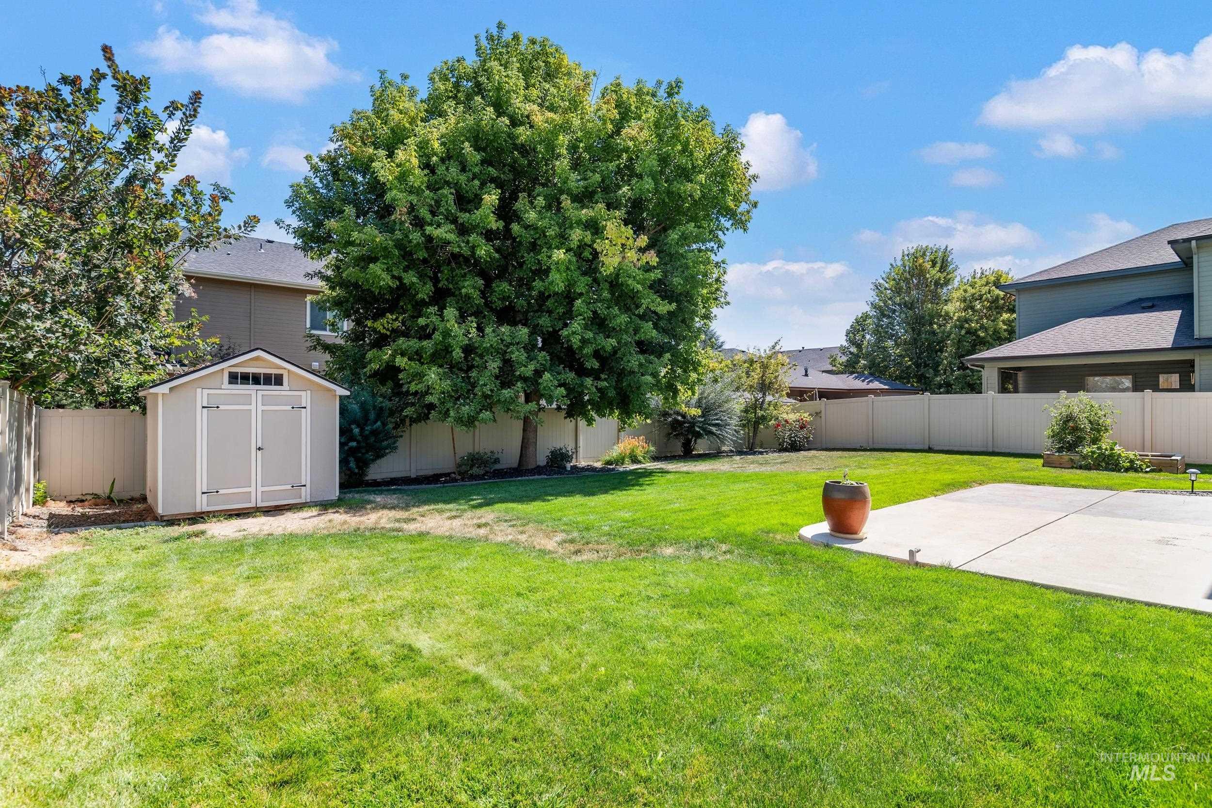 Fenced backyard featuring a storage unit