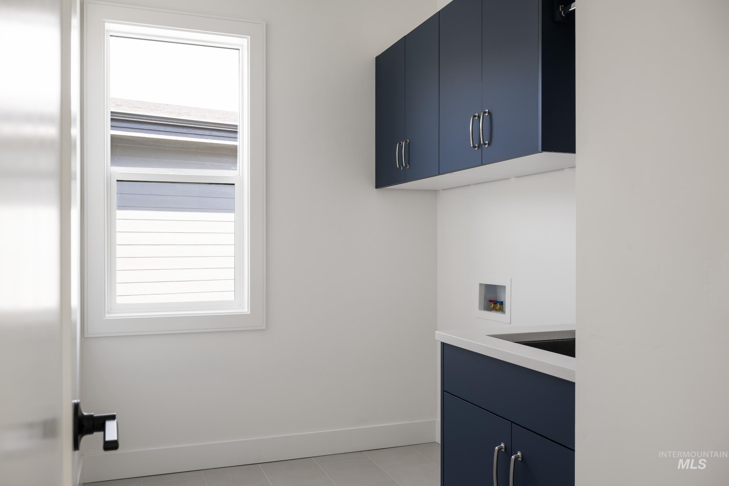 Laundry room with cabinet space, washer hookup, and light tile patterned flooring