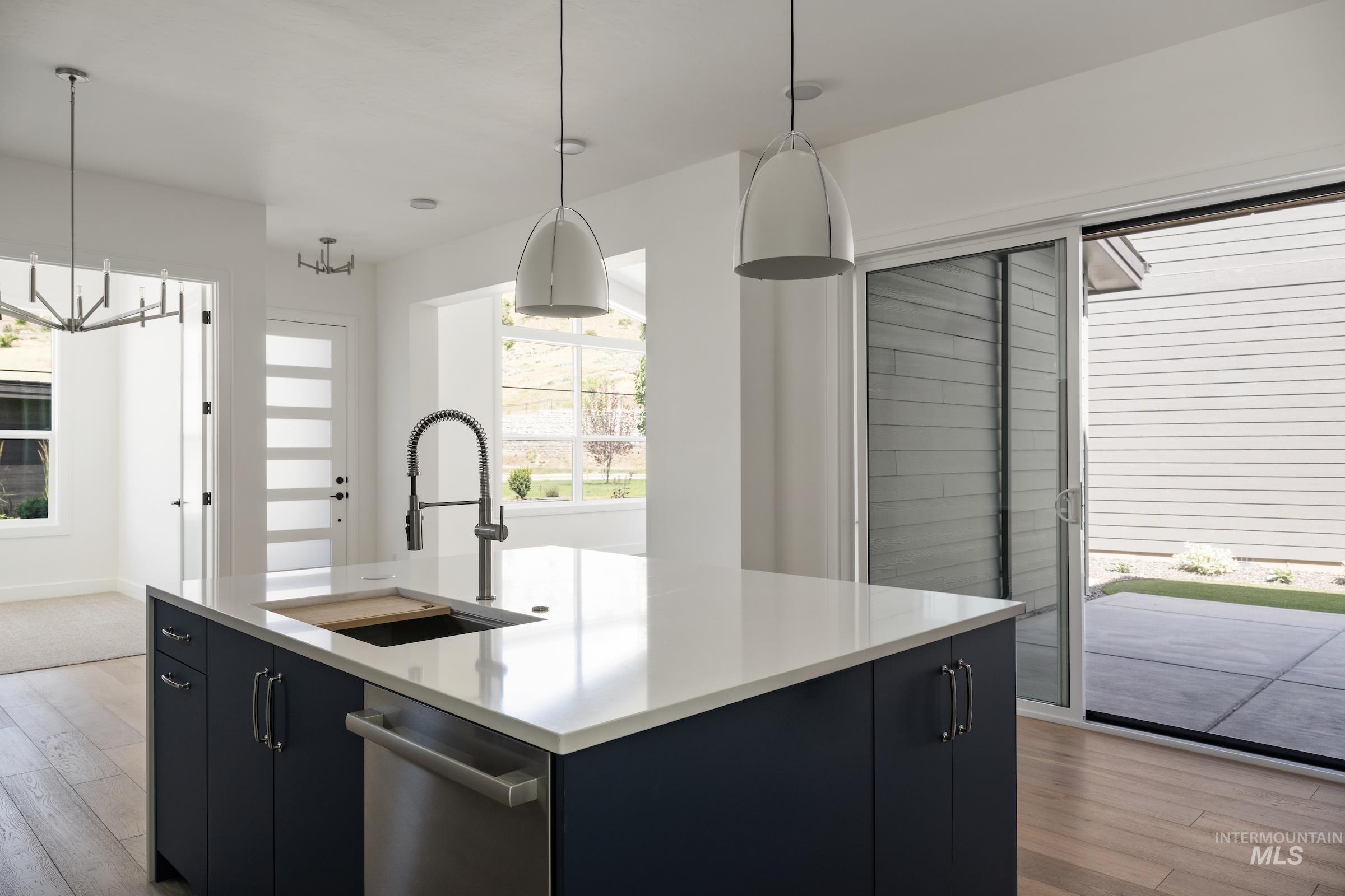 Kitchen with dark cabinets, light wood-style flooring, and pendant lighting