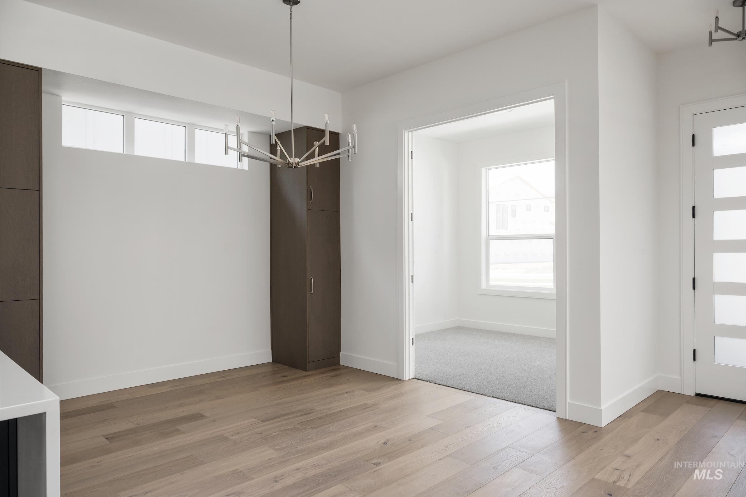Unfurnished dining area with a chandelier, plenty of natural light, and light wood-style floors