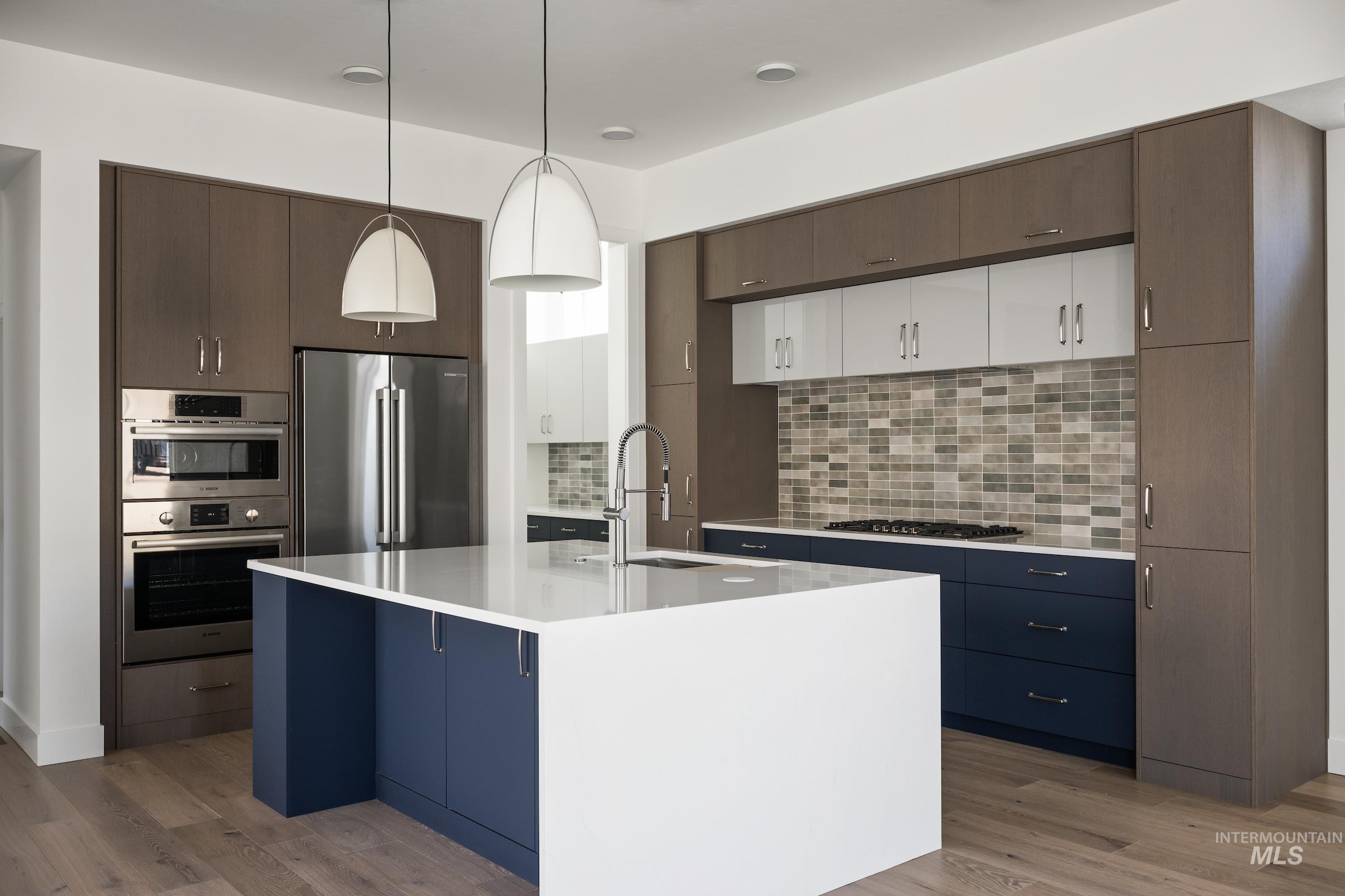 Kitchen with appliances with stainless steel finishes, light countertops, light wood-type flooring, and tasteful backsplash