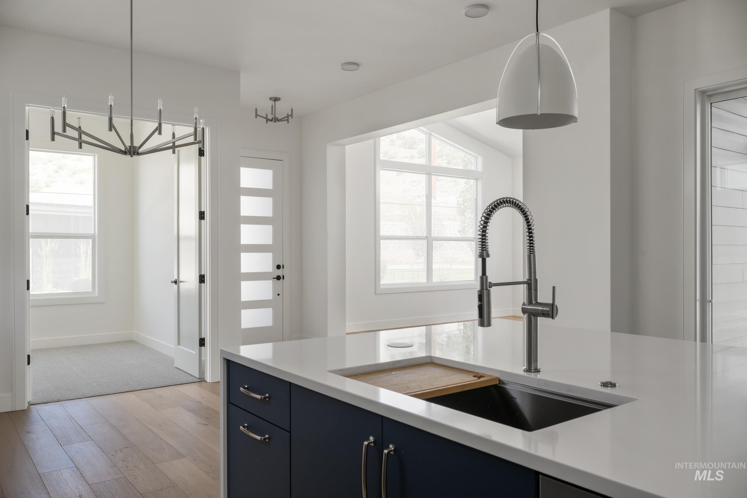 Kitchen with light countertops, light wood-type flooring, pendant lighting, and healthy amount of natural light