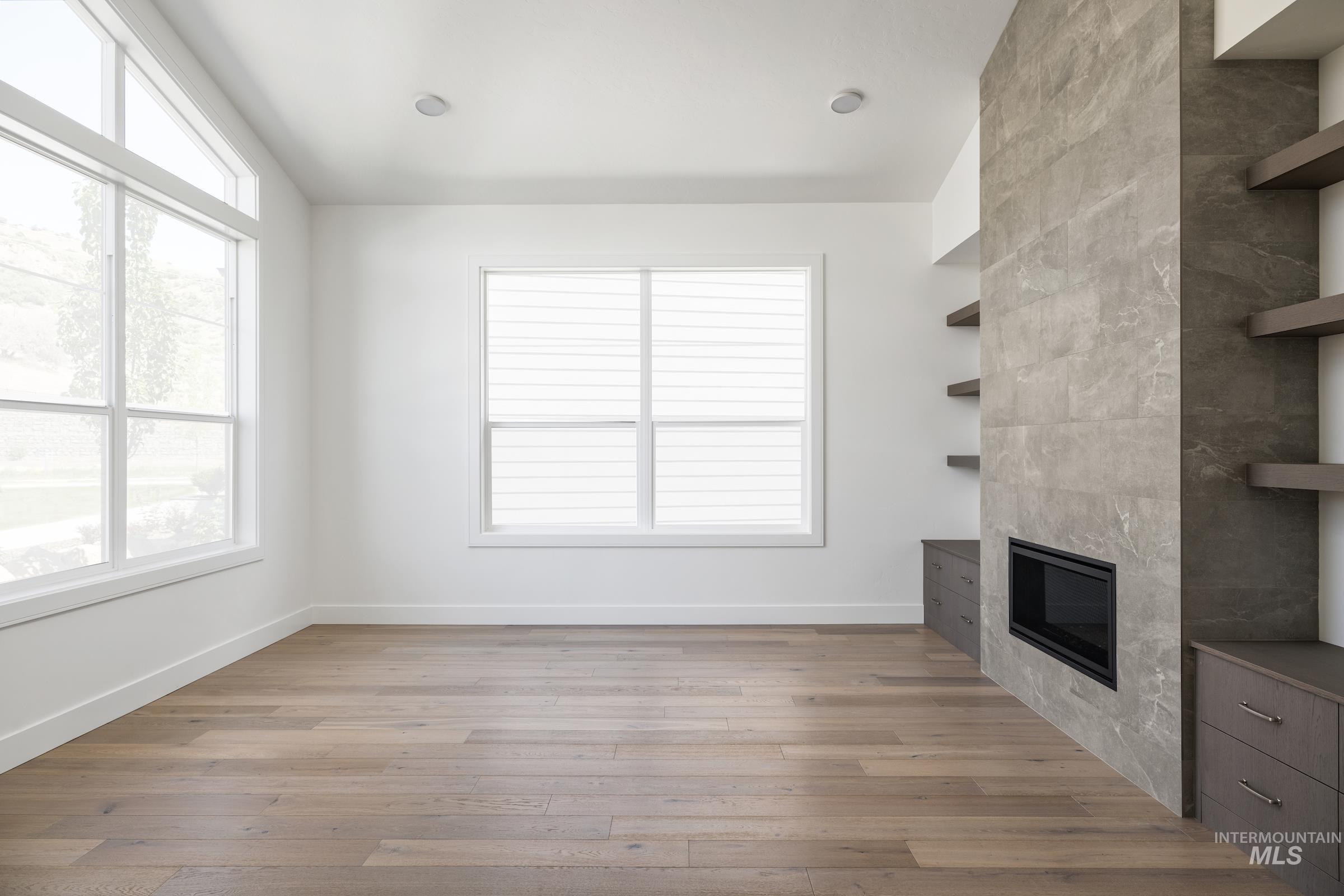 Unfurnished living room with a fireplace, healthy amount of natural light, and light wood finished floors