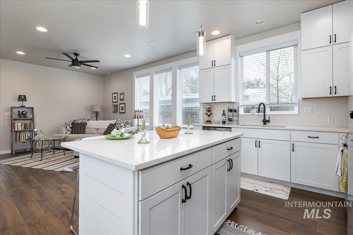 Kitchen with white cabinetry, open floor plan, decorative backsplash, and dark wood-style flooring