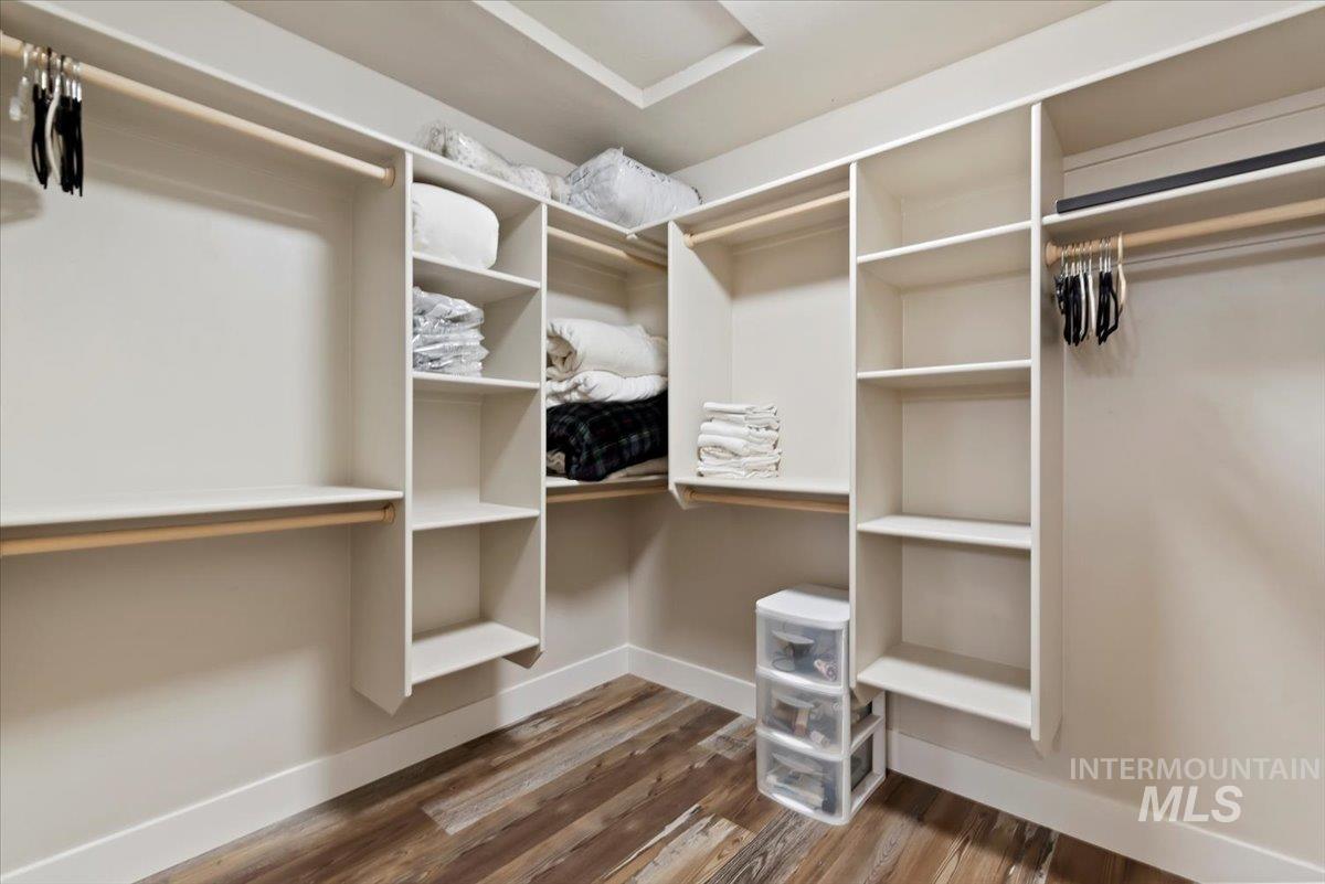 Walk in closet featuring attic access and dark wood-style flooring