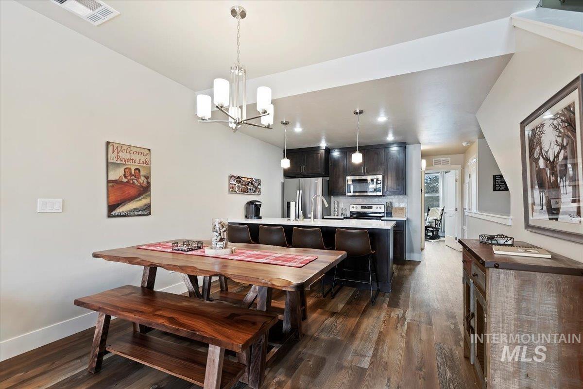 Dining space featuring dark wood-type flooring and hanging lights