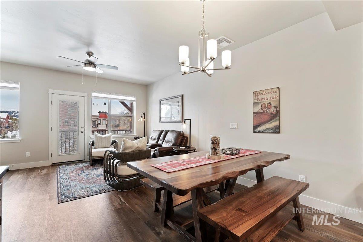 Dining space featuring ceiling fan, dark wood-style flooring, and a chandelier