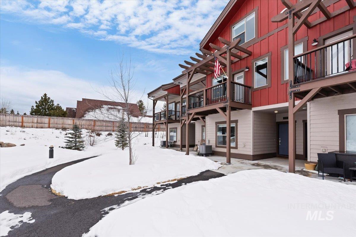 Yard covered in snow with a patio area, a wooden deck, and a balcony