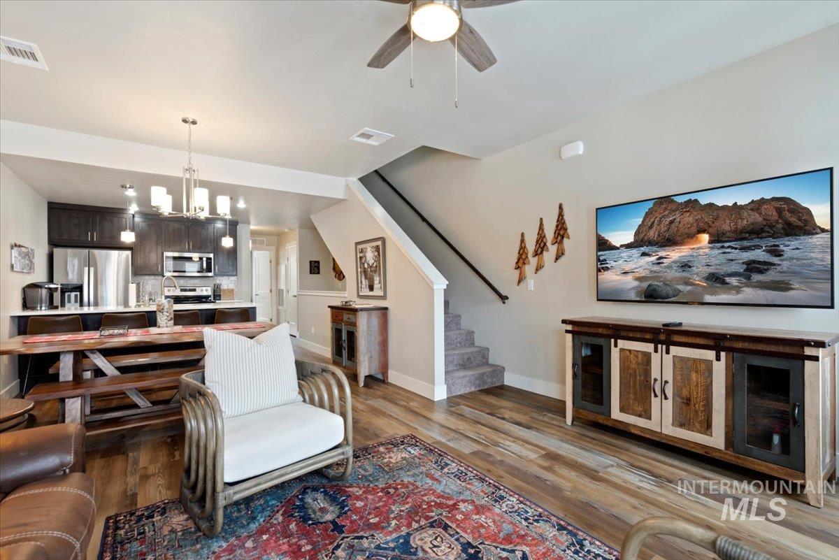 Living area with a chandelier, light wood finished floors, and a ceiling fan