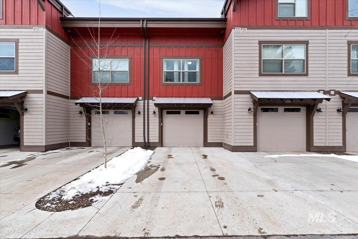 View of front of house with board and batten siding, an attached garage, and driveway