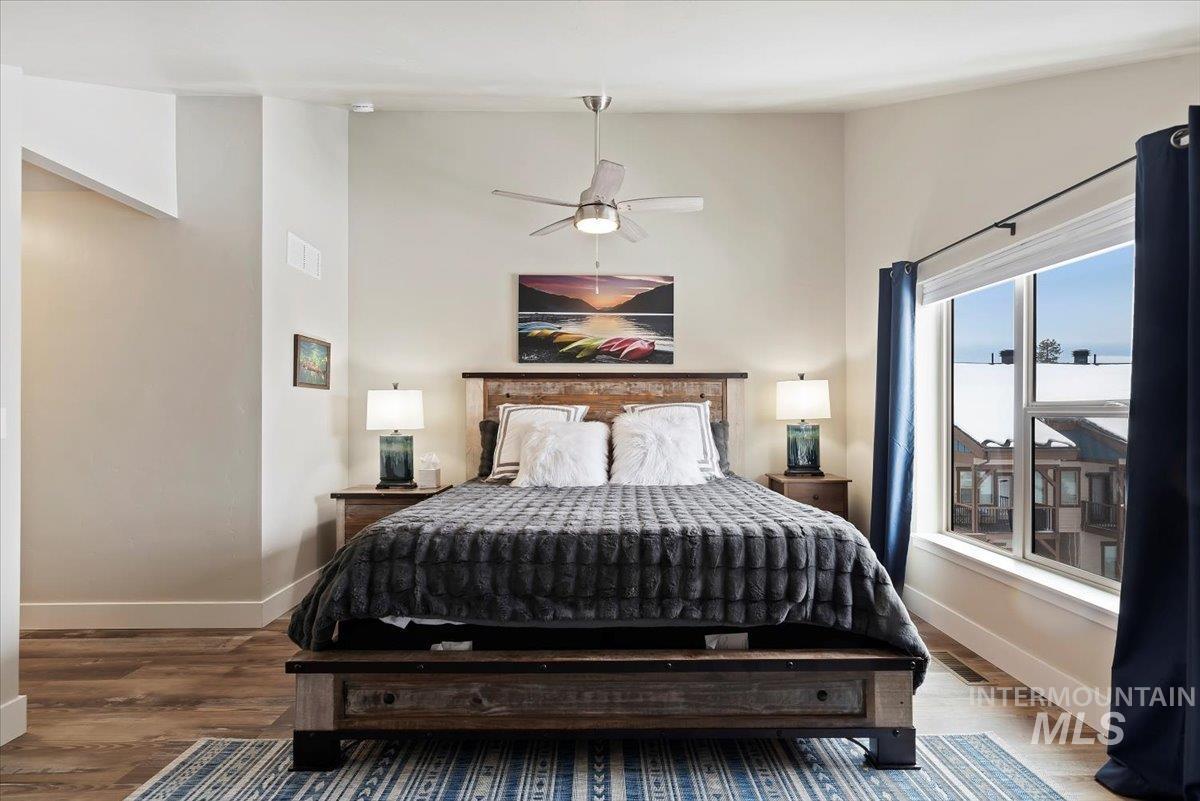 Bedroom with wood finished floors, a ceiling fan, and lofted ceiling
