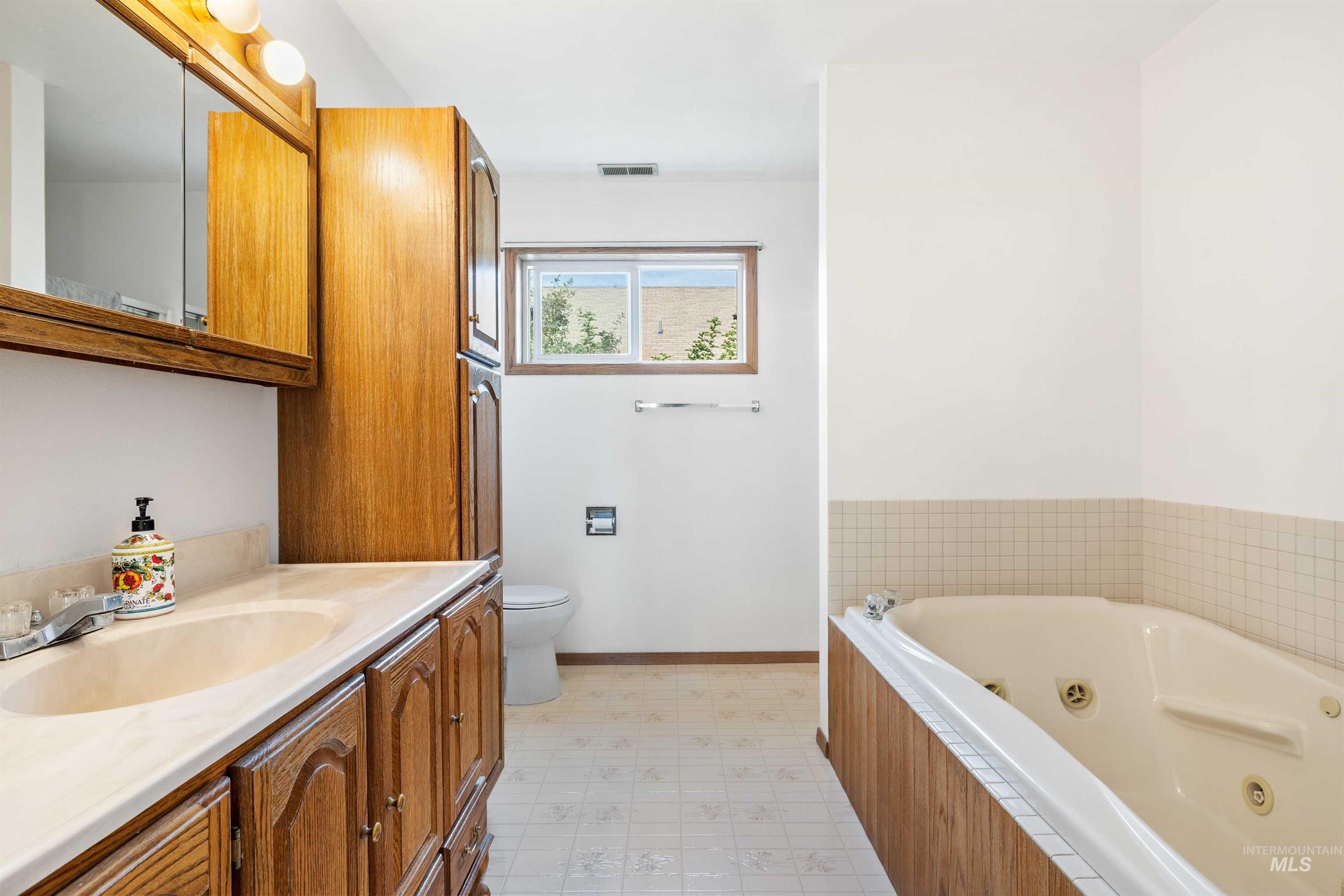 Full bathroom with a tub with jets, vanity, and light flooring