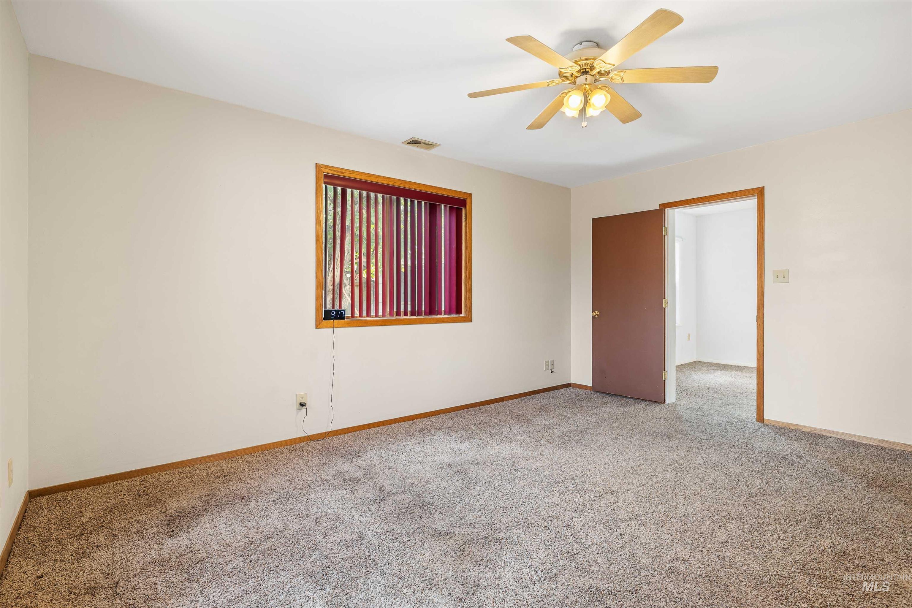 Carpeted spare room with baseboards and a ceiling fan