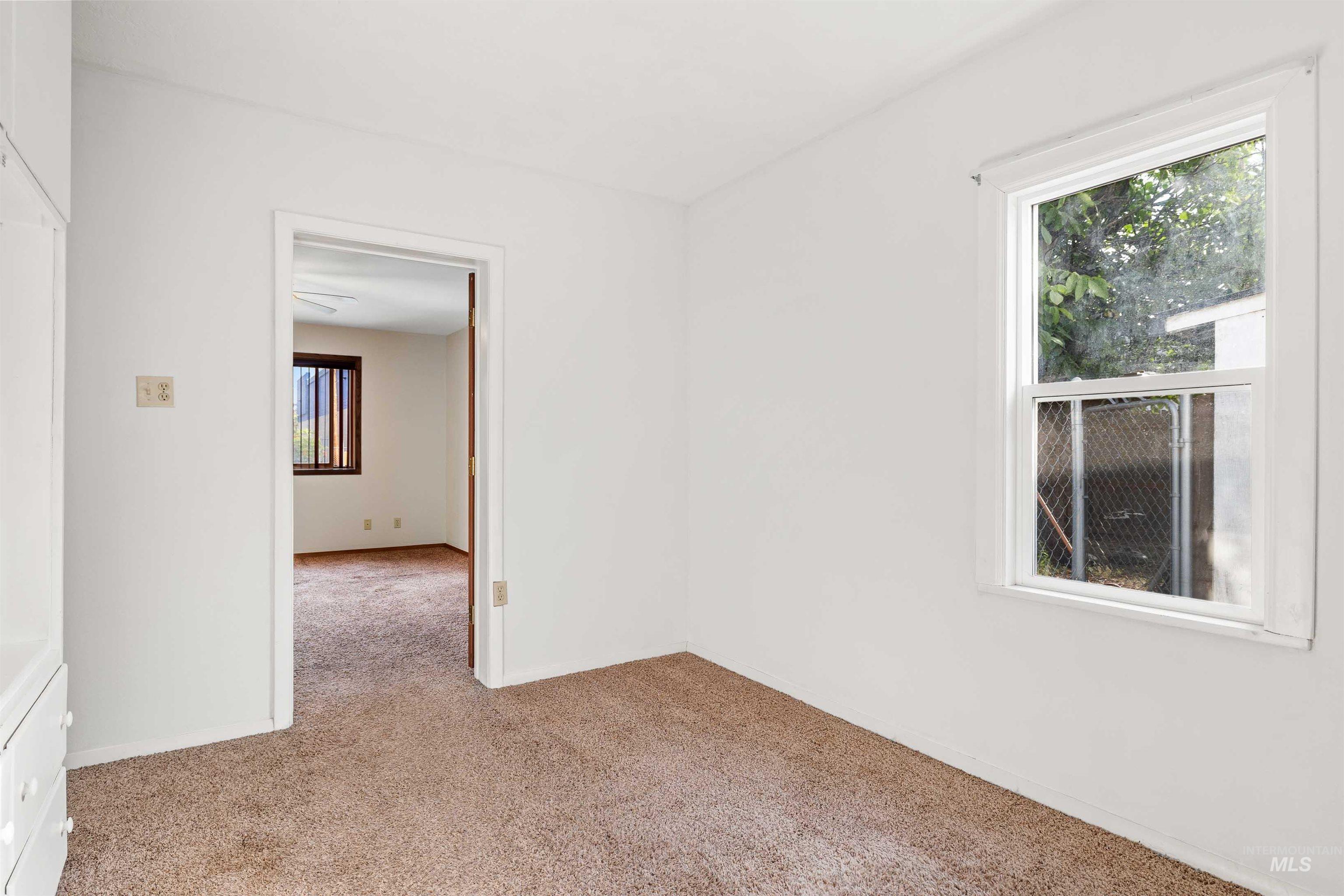 Empty room with light colored carpet and baseboards