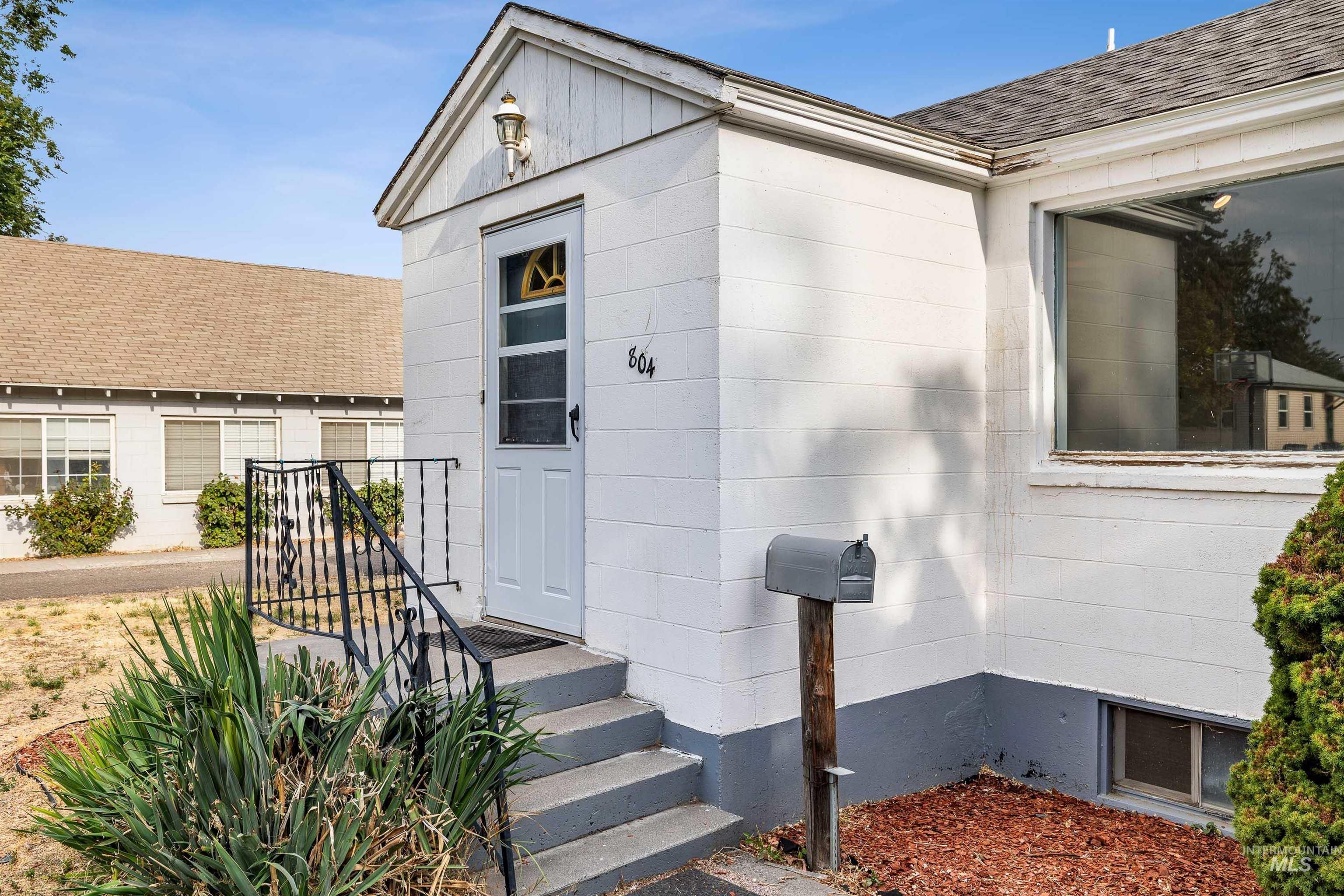 Doorway to property with a shingled roof and concrete block siding