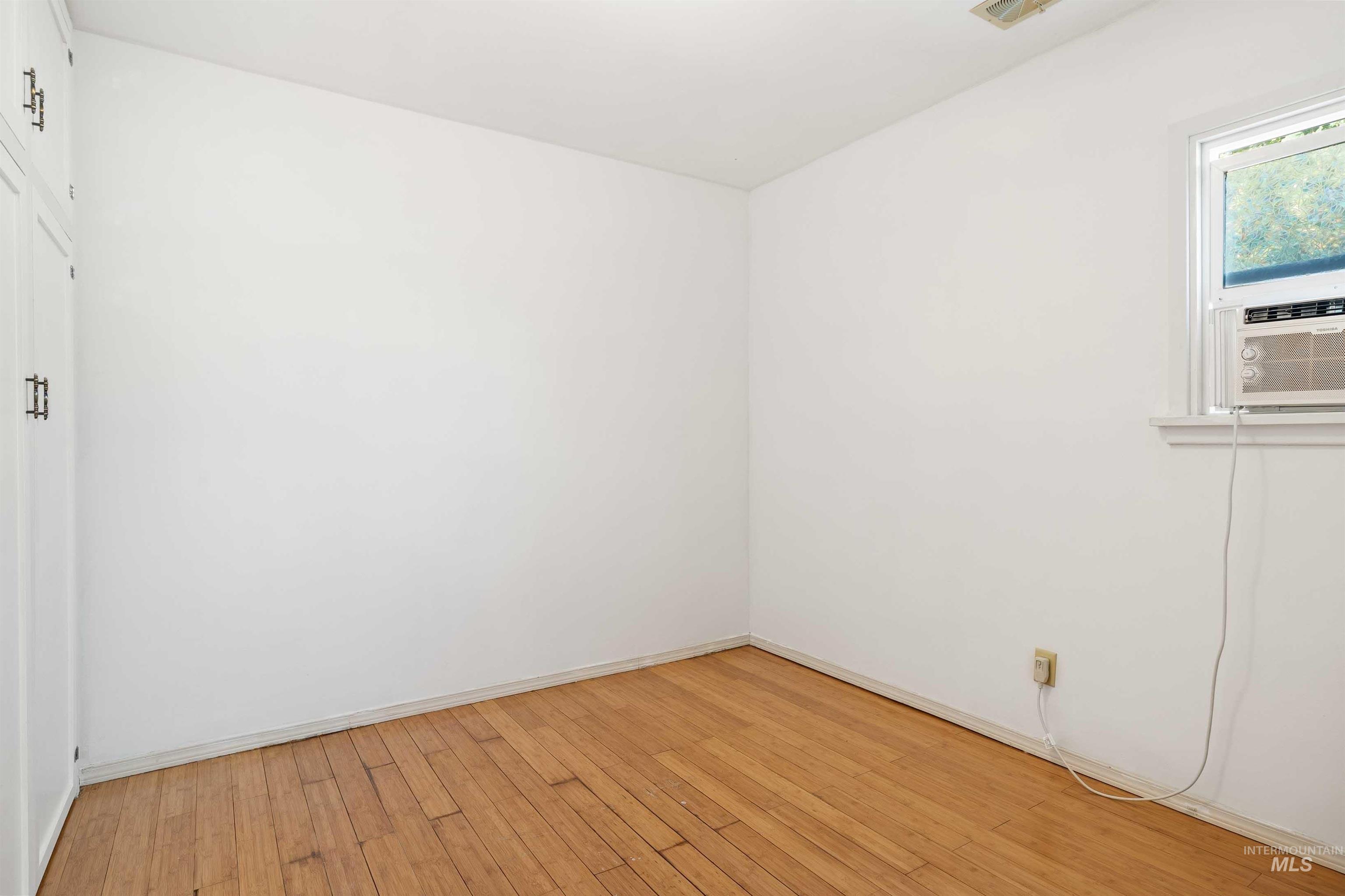Empty room featuring light wood finished floors and cooling unit