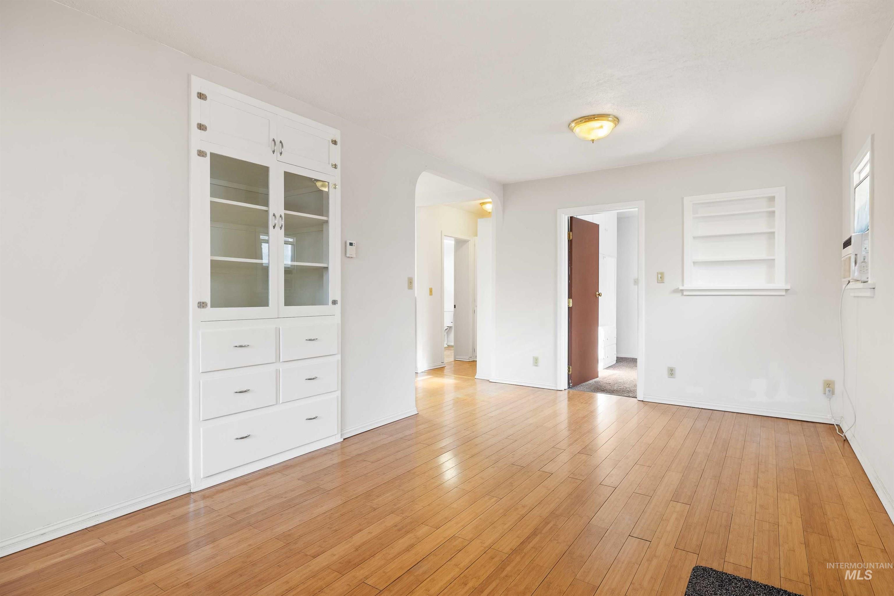 Empty room with light wood-type flooring and arched walkways