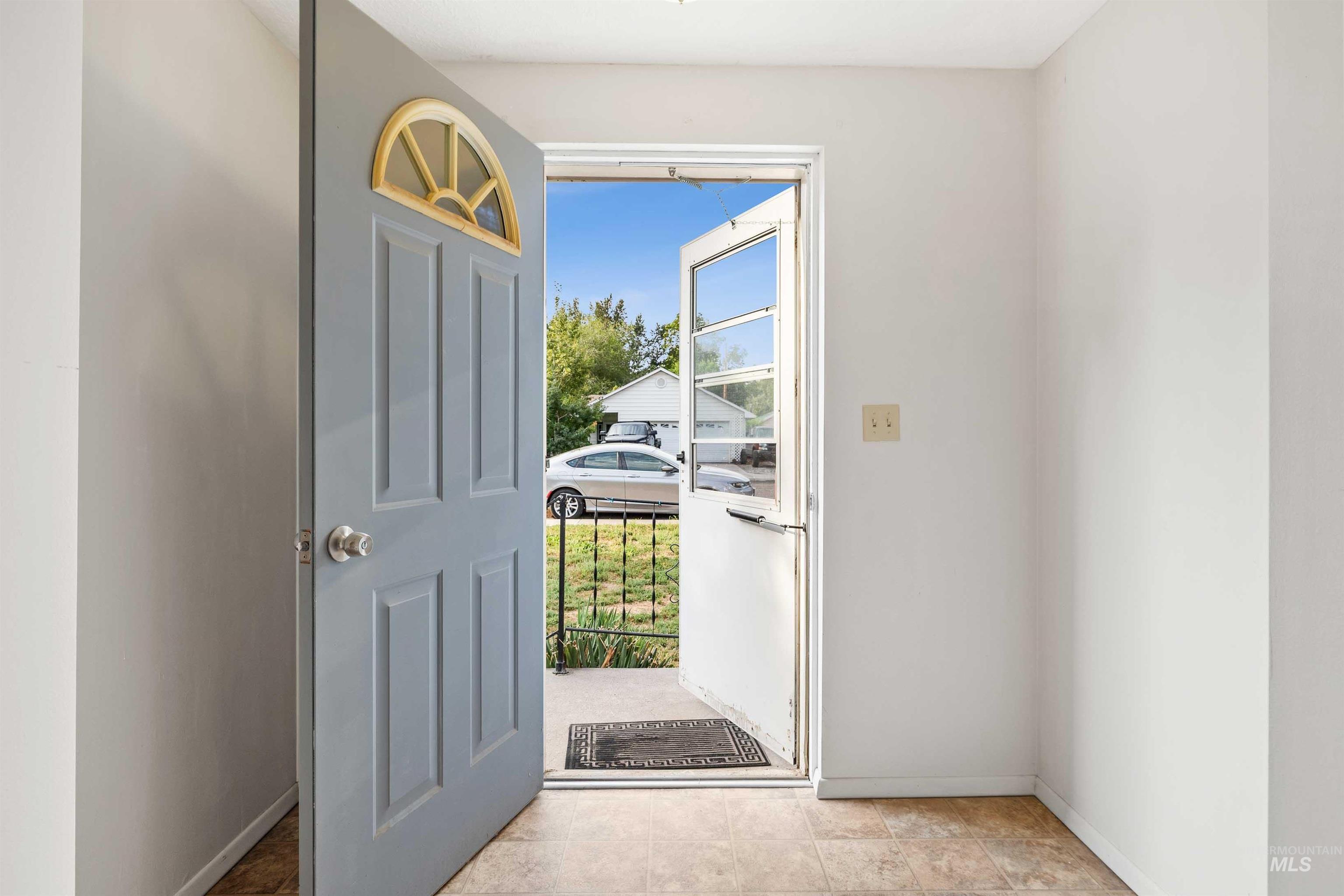 Doorway with baseboards and tile patterned flooring
