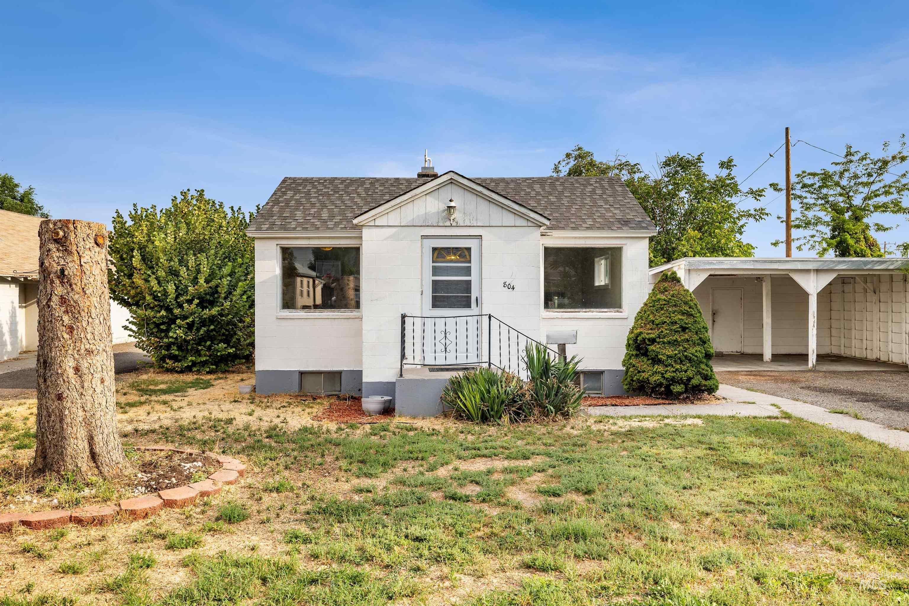 Bungalow-style home with roof with shingles, a front yard, and driveway