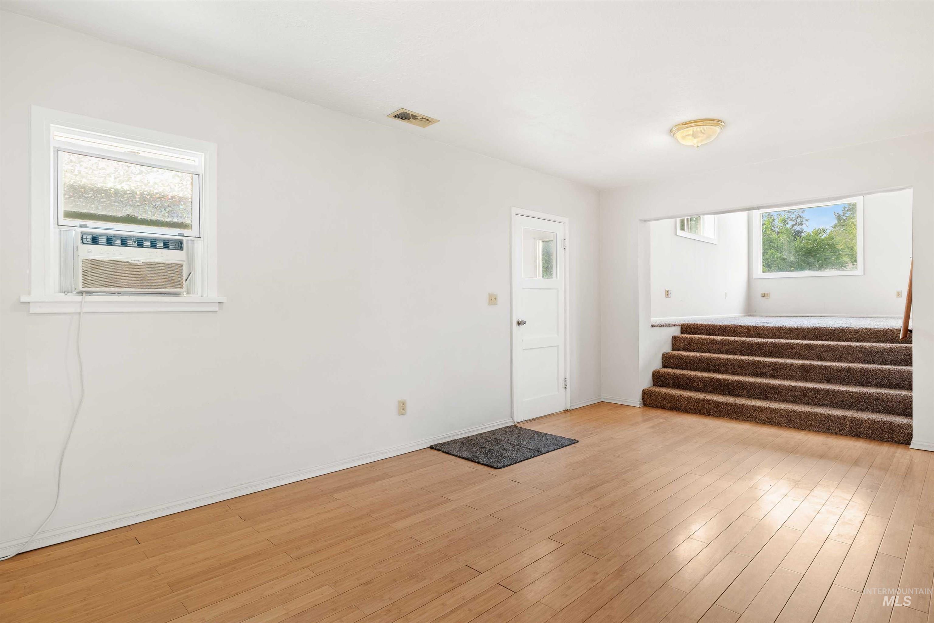 Entrance foyer with light wood-type flooring, stairway, and cooling unit