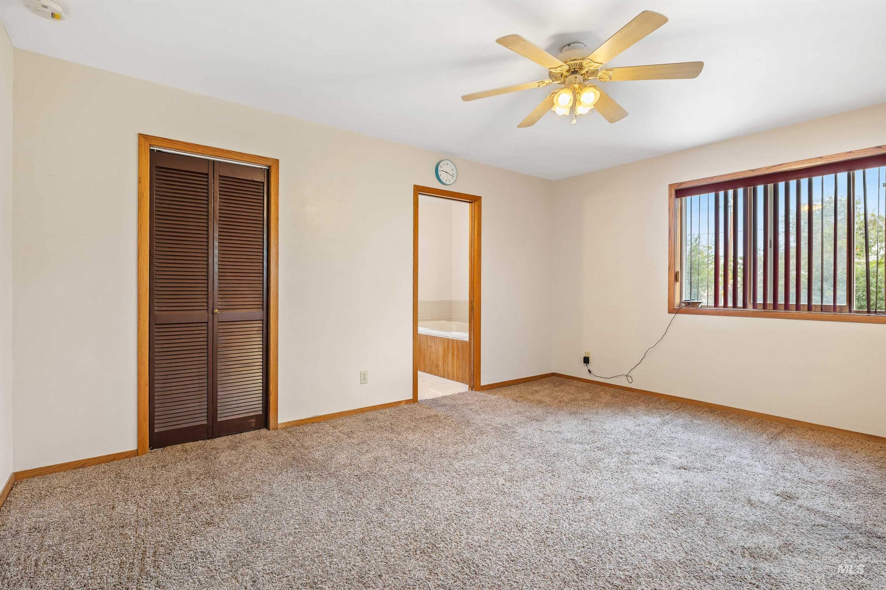 Unfurnished bedroom with a closet, light carpet, a ceiling fan, and ensuite bathroom