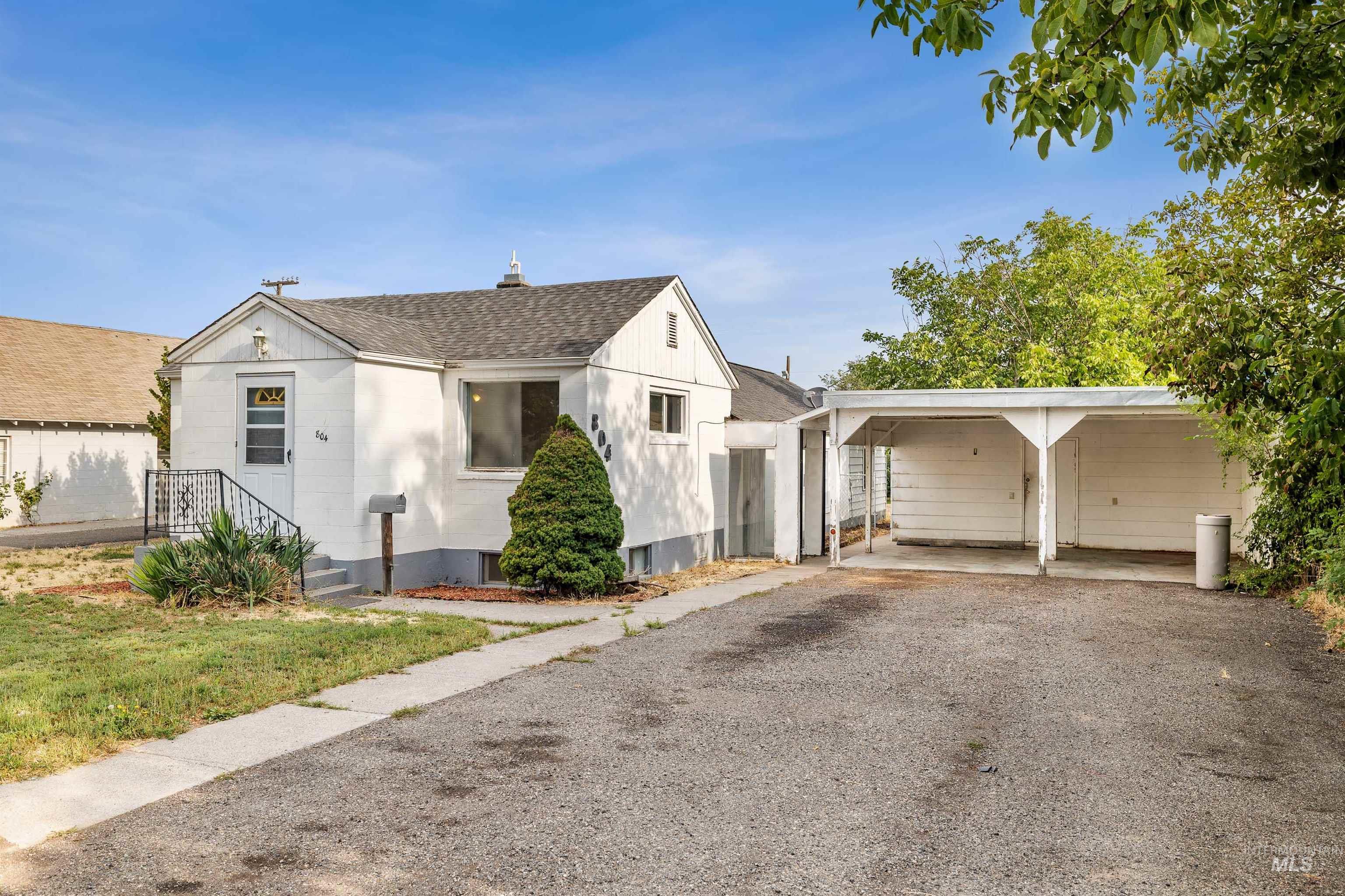 Bungalow-style house featuring a chimney, roof with shingles, and gravel driveway