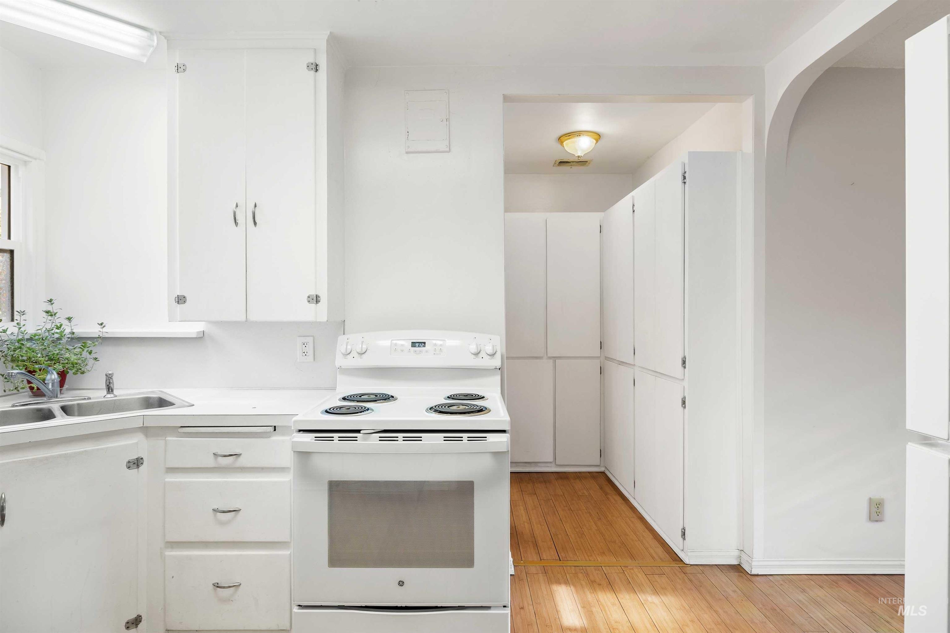 Kitchen with white appliances, white cabinets, light countertops, and light wood-style flooring