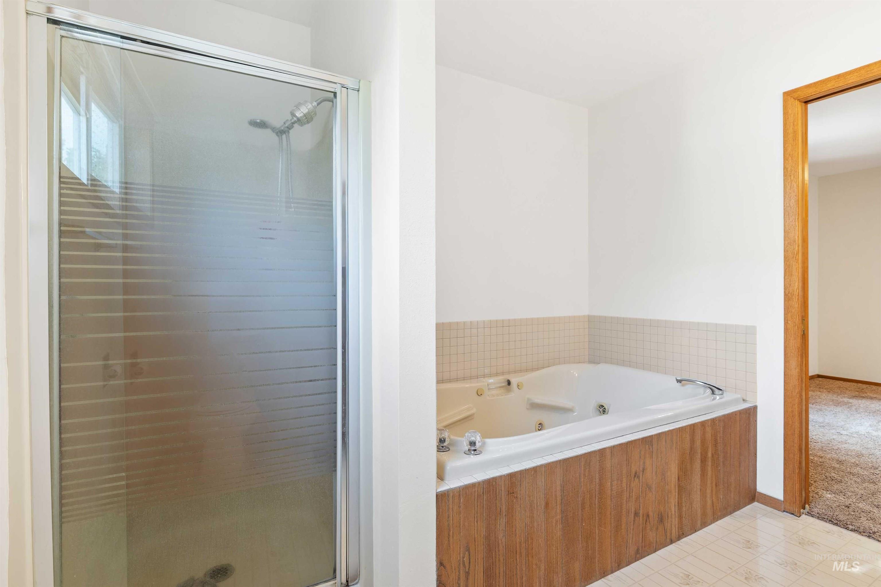 Bathroom with a shower stall, a tub with jets, and light tile patterned floors