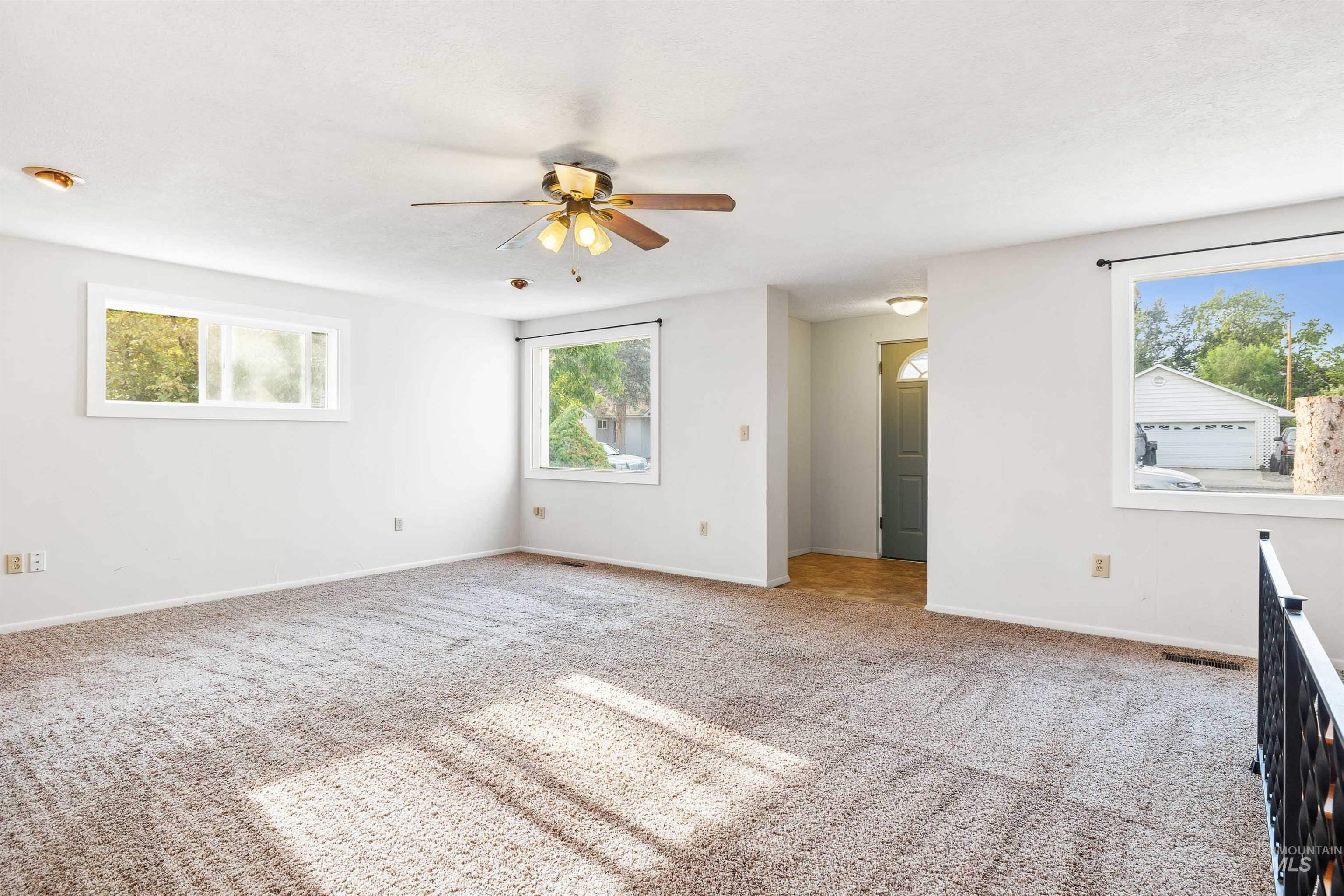 Empty room with light colored carpet and ceiling fan