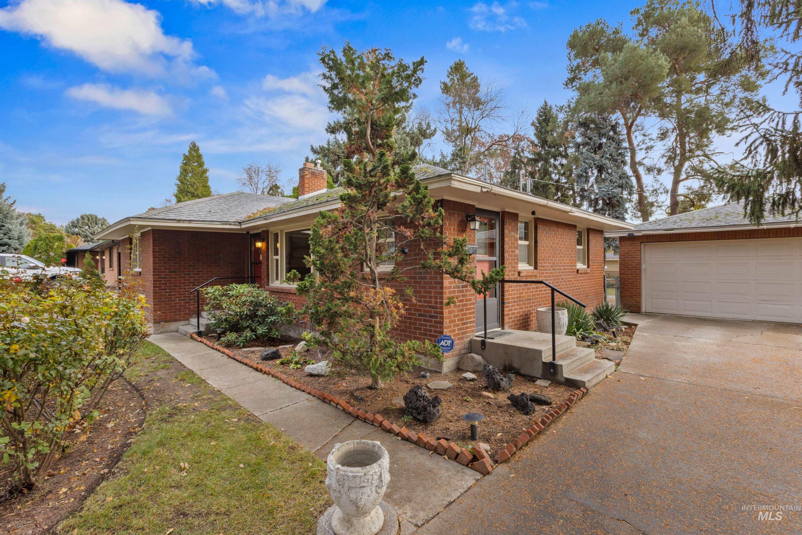 Ranch-style home with brick siding, a garage, a chimney, concrete driveway, and an outbuilding