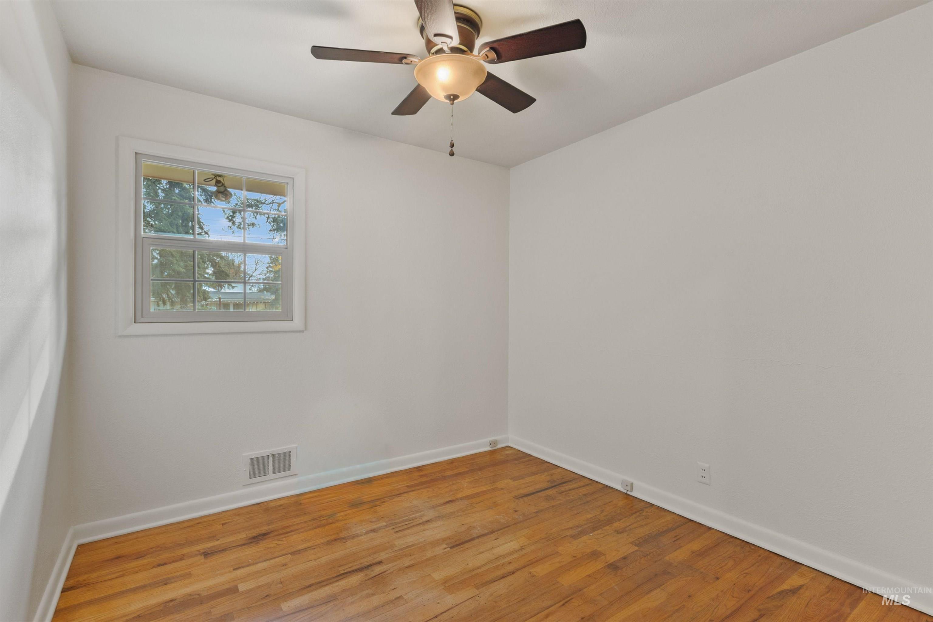Empty room with wood finished floors and ceiling fan